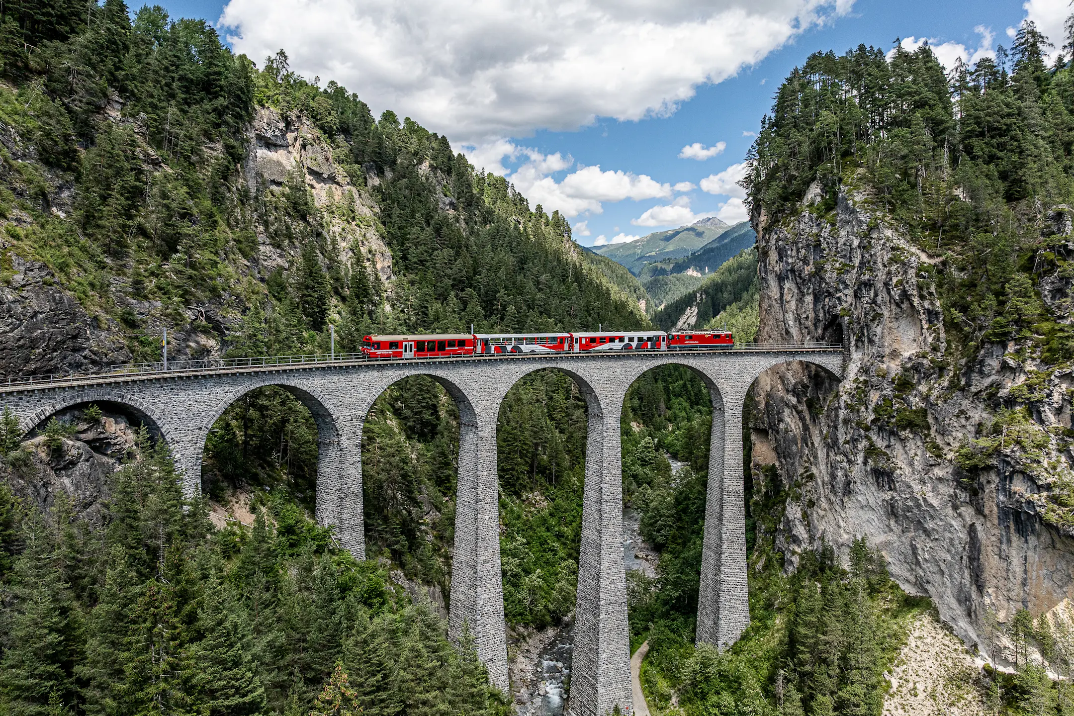 Das Viaduktshuttle der RhB fährt auf dem Landwasserviadukt Sommer, bergige Landschaft