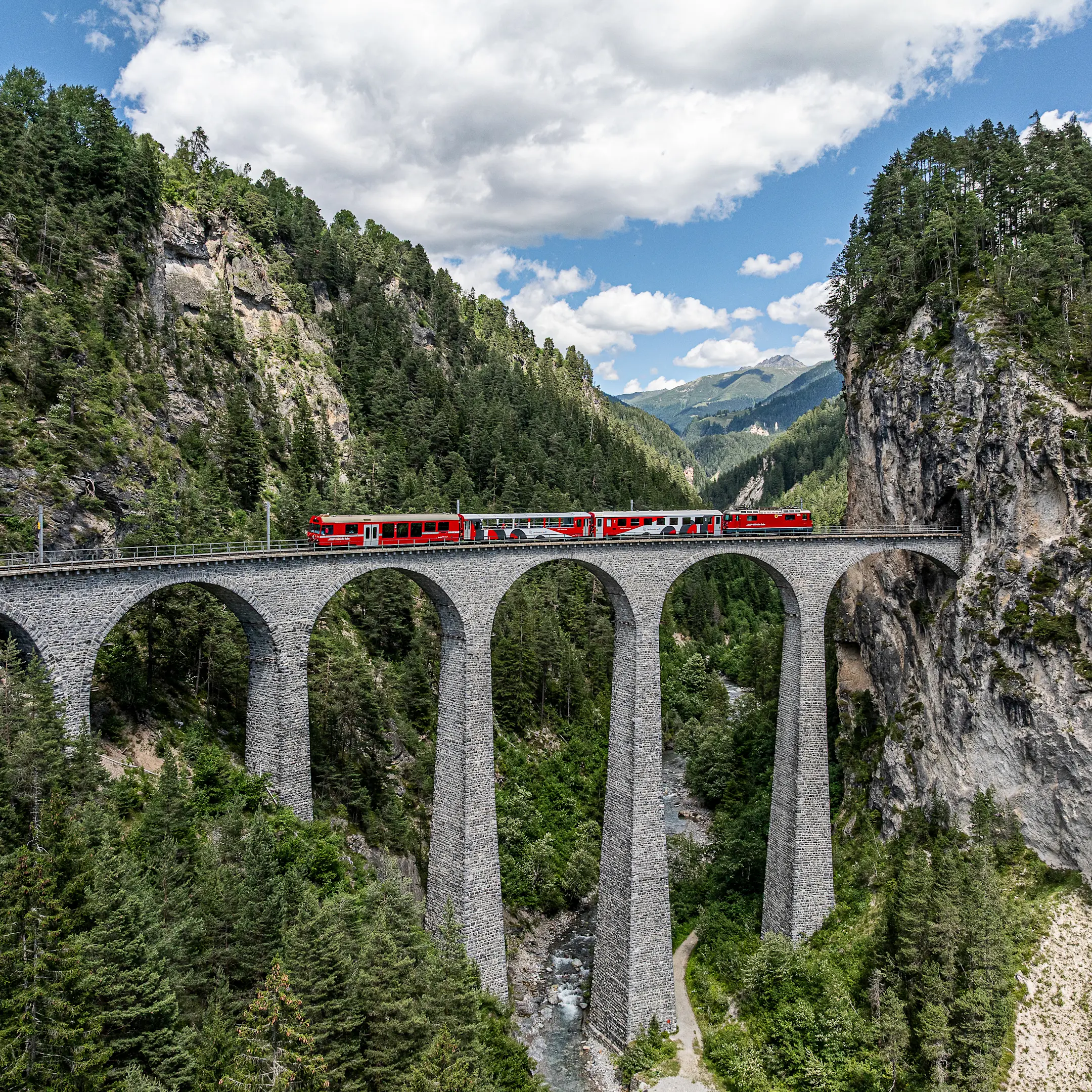 Das Viaduktshuttle der RhB fährt auf dem Landwasserviadukt Sommer, bergige Landschaft