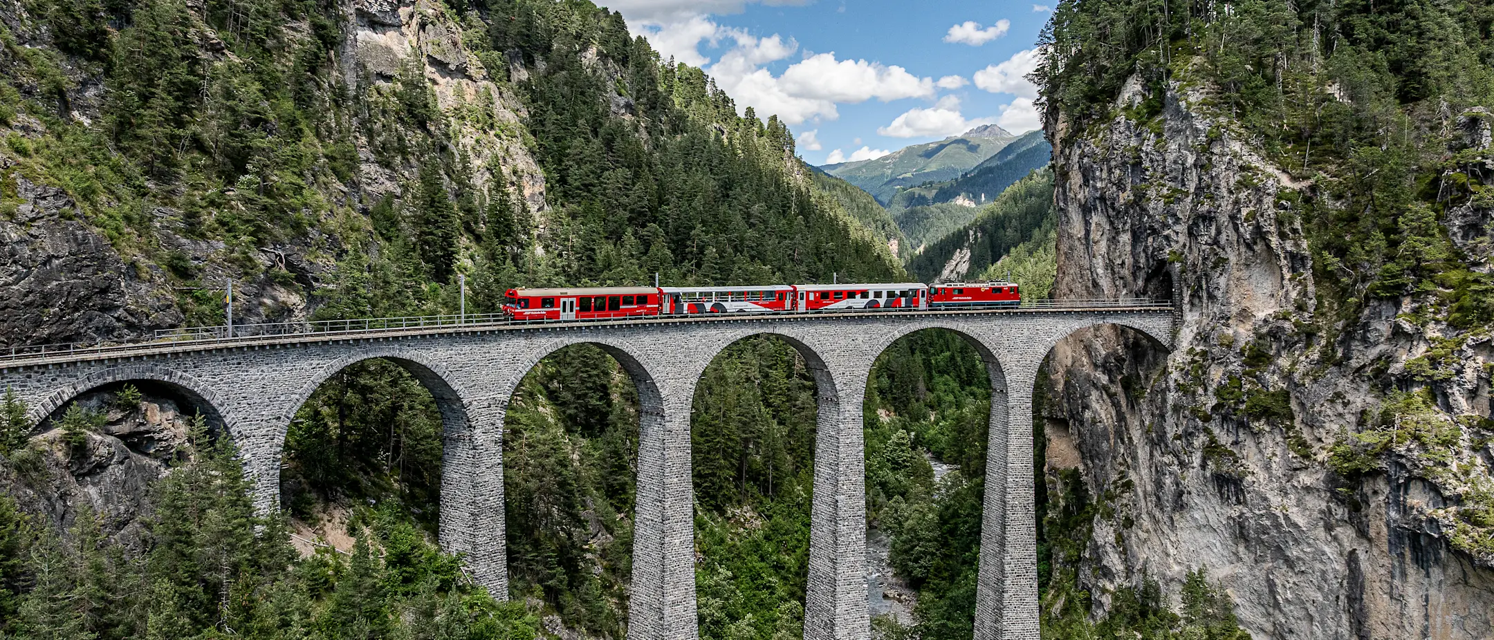 Das Viaduktshuttle der RhB fährt auf dem Landwasserviadukt Sommer, bergige Landschaft