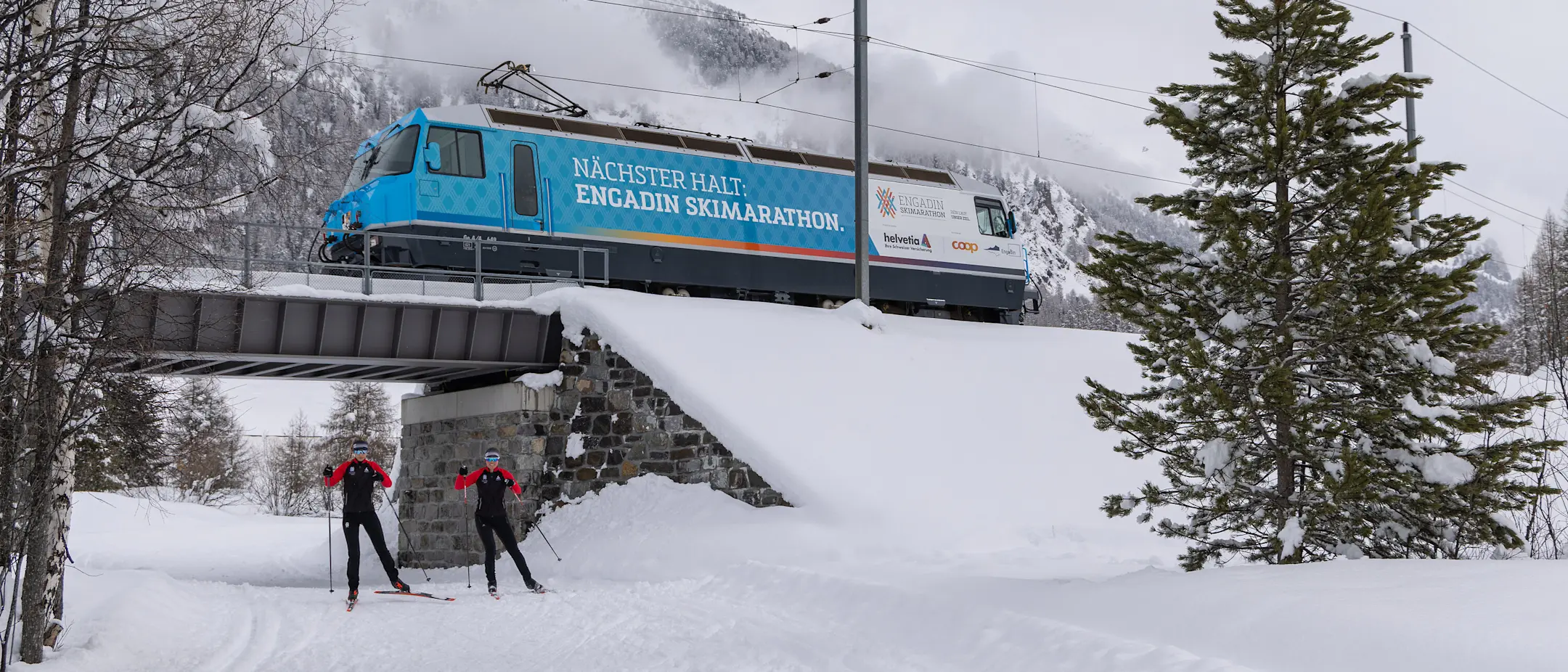 Die Werbelokomotive mit Sujet des Engadin Skimarathon überquert eine Brücke im Oberengadin.
