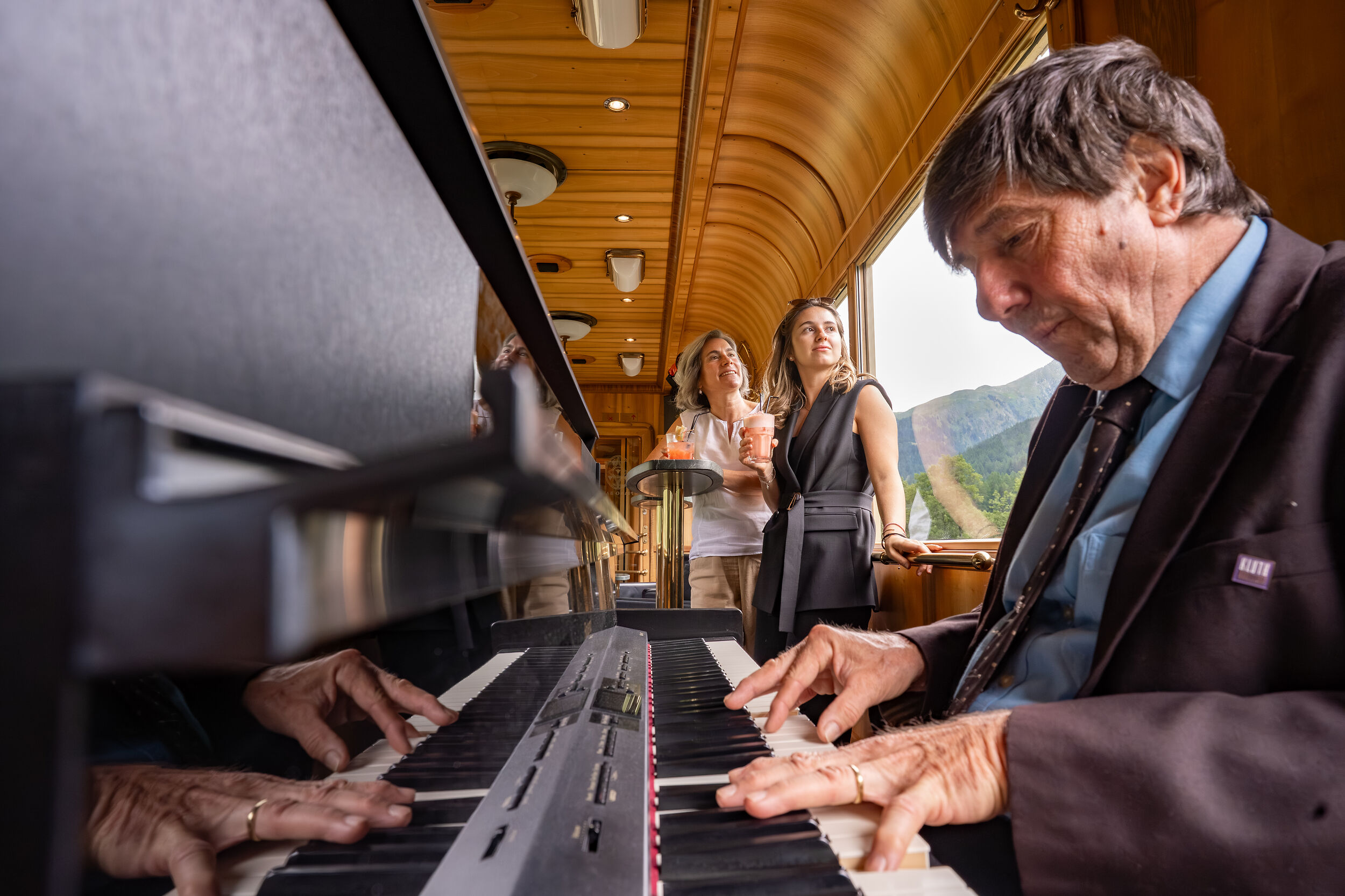 Ein Pianist spielt Piano und zwei Frauen hören zu. 