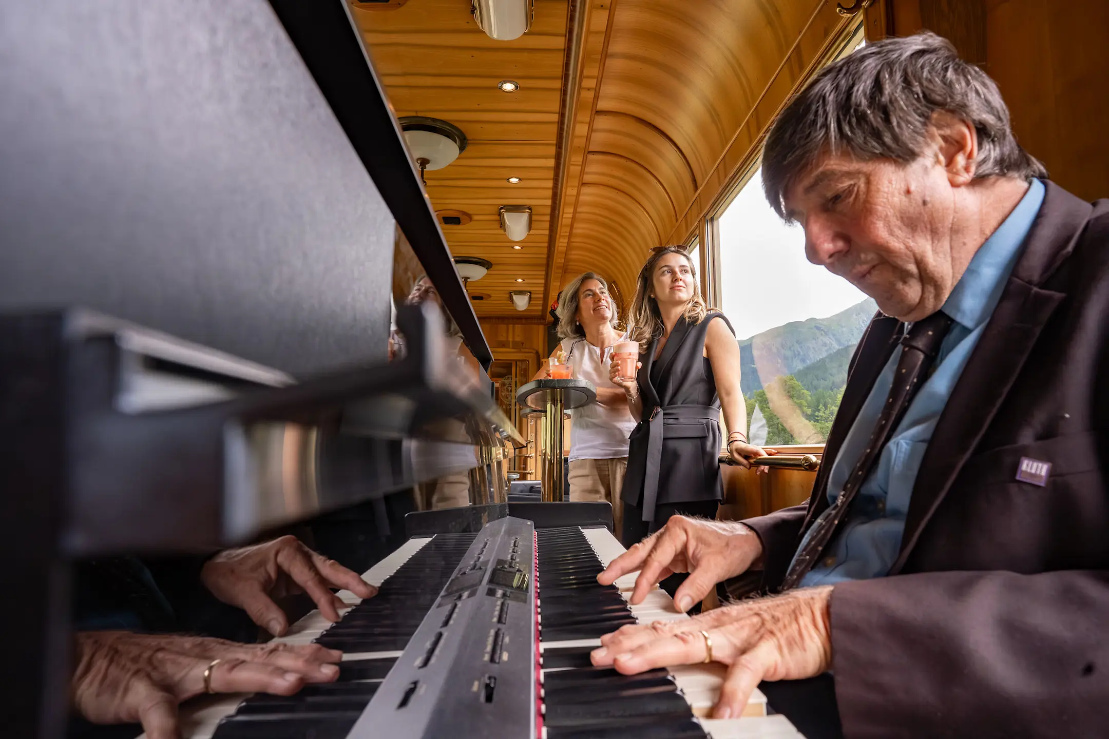 Ein Pianist spielt Piano und zwei Frauen hören zu.