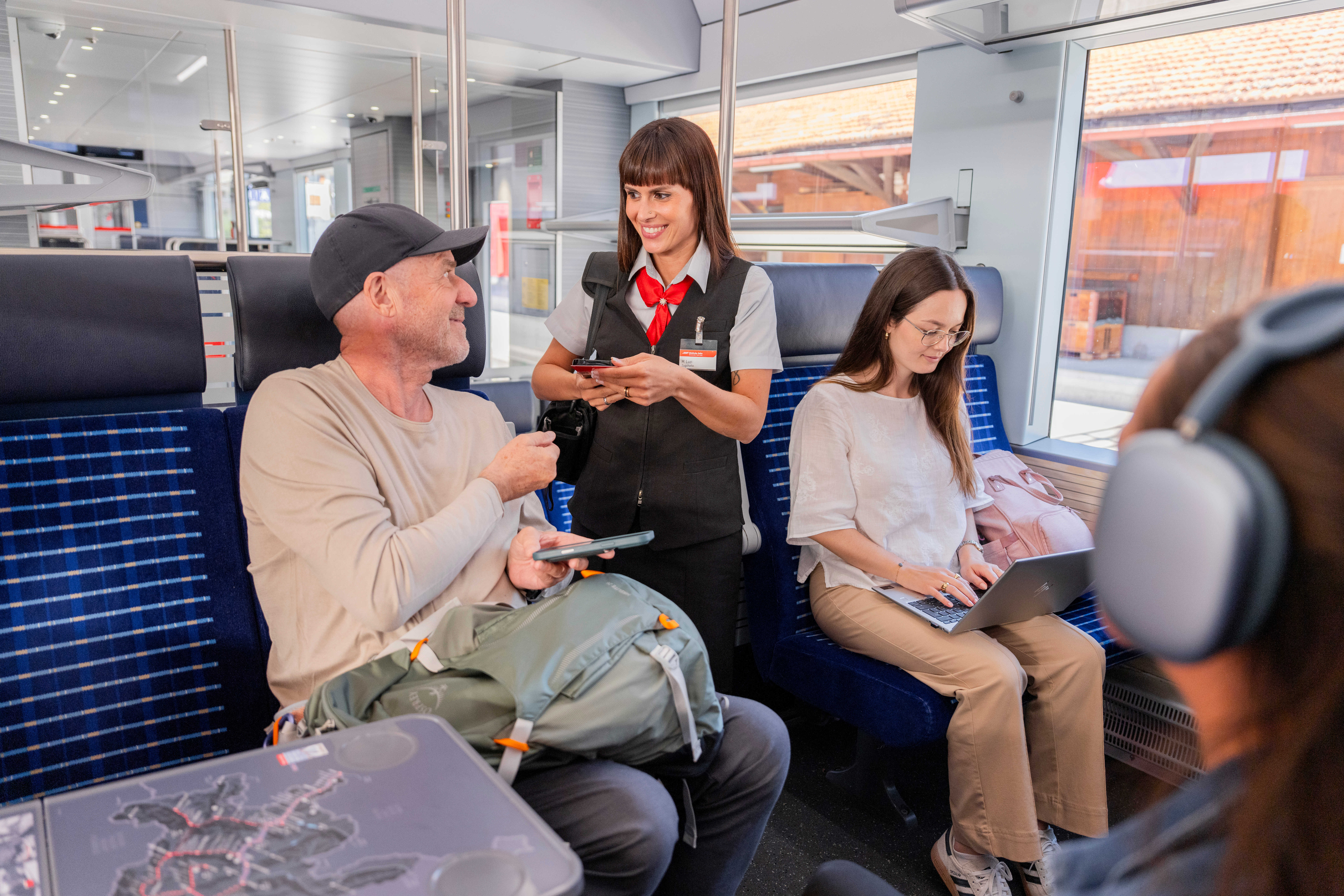 Zugbegleiterin kontrolliert Ticket bei Fahrgast