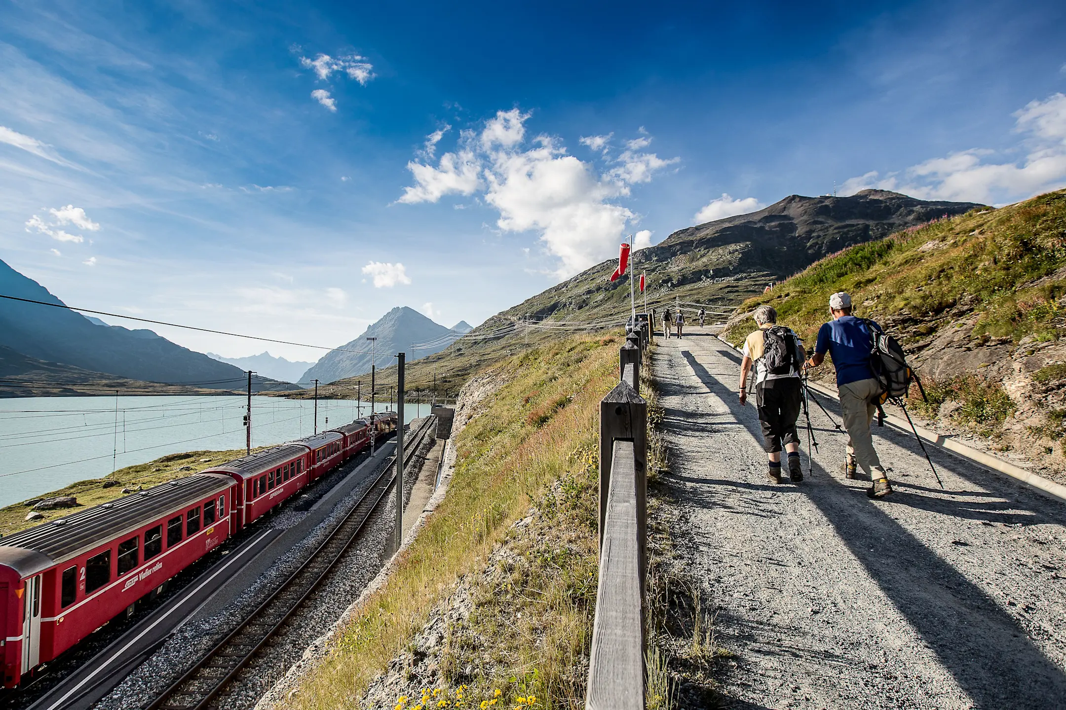 Zwei Personen wandern beim Lago Bianco oberhalb der Gleise.