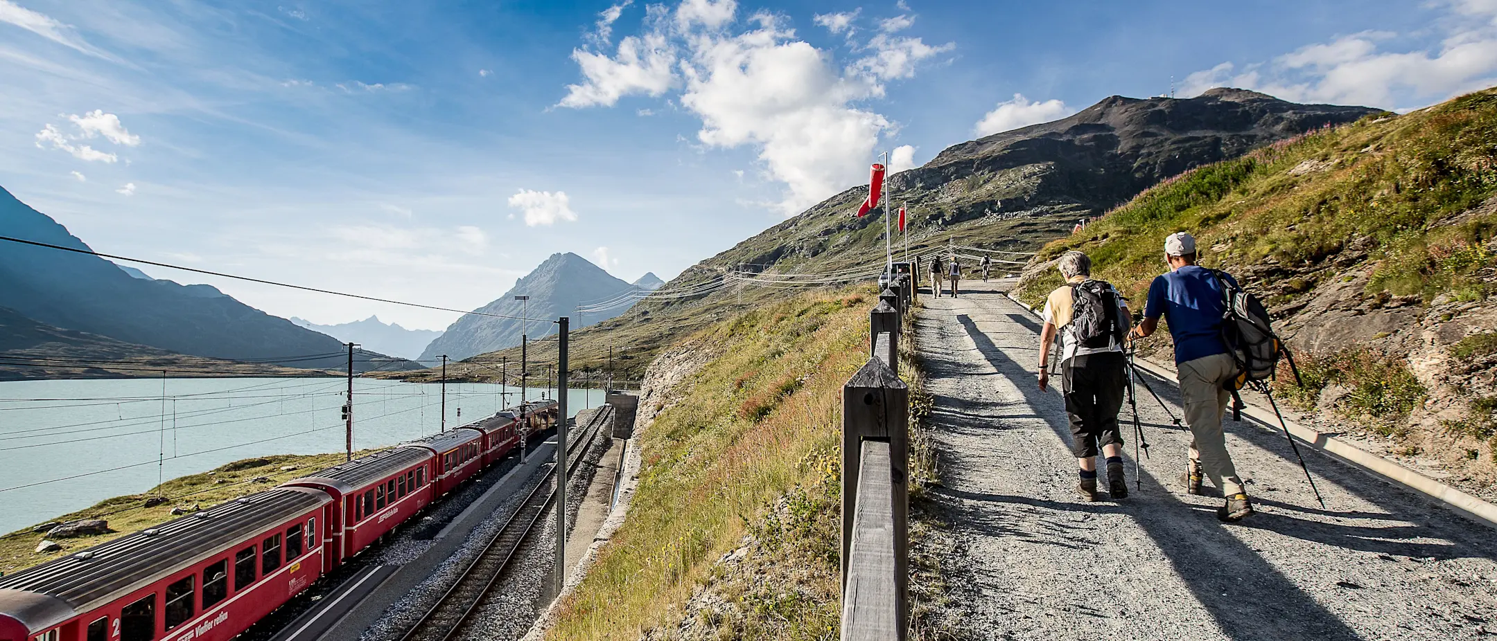 Zwei Personen wandern beim Lago Bianco oberhalb der Gleise.