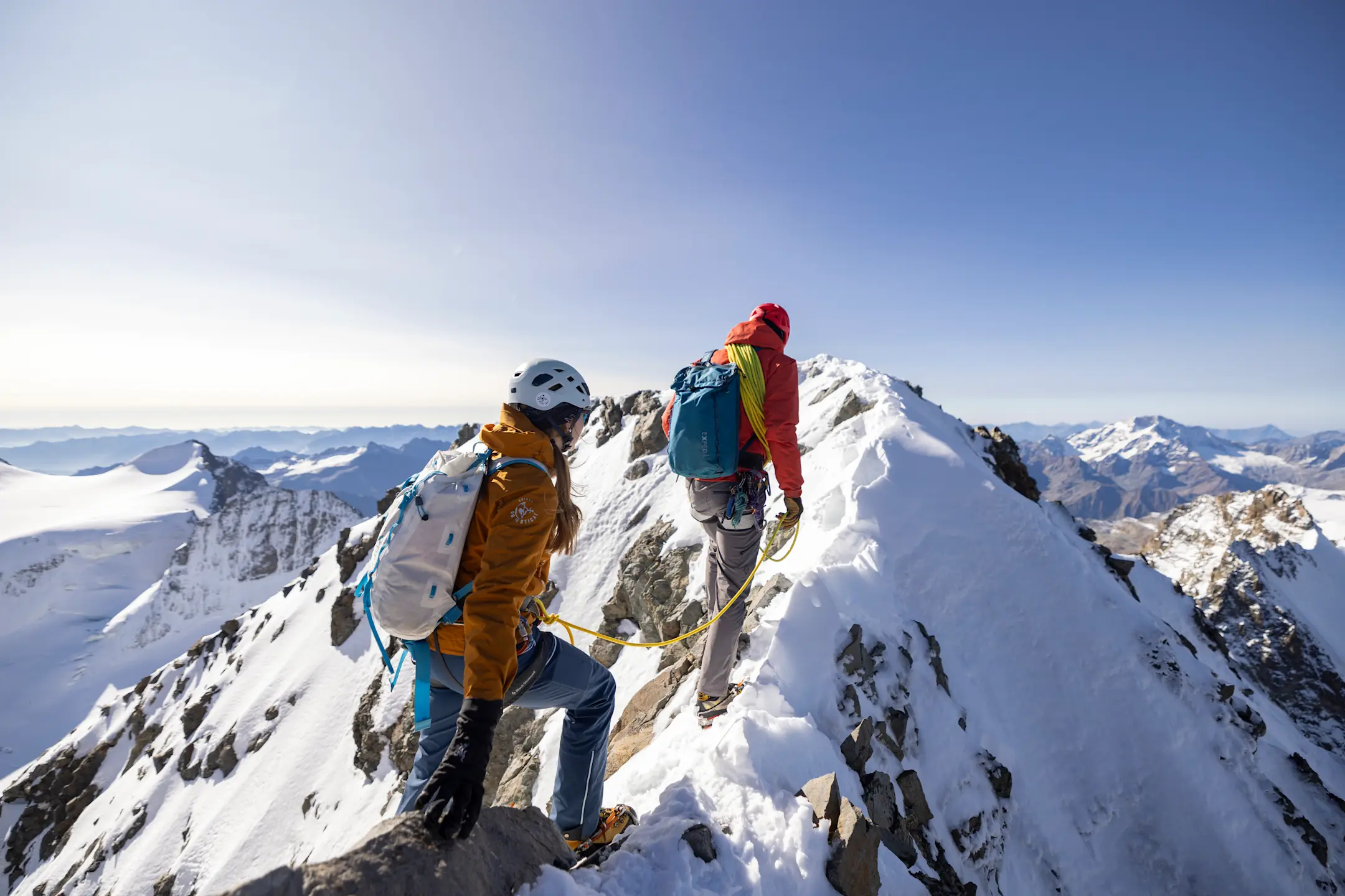 Zwei Bergsteiger auf einem Berggipfel mit Sonne
