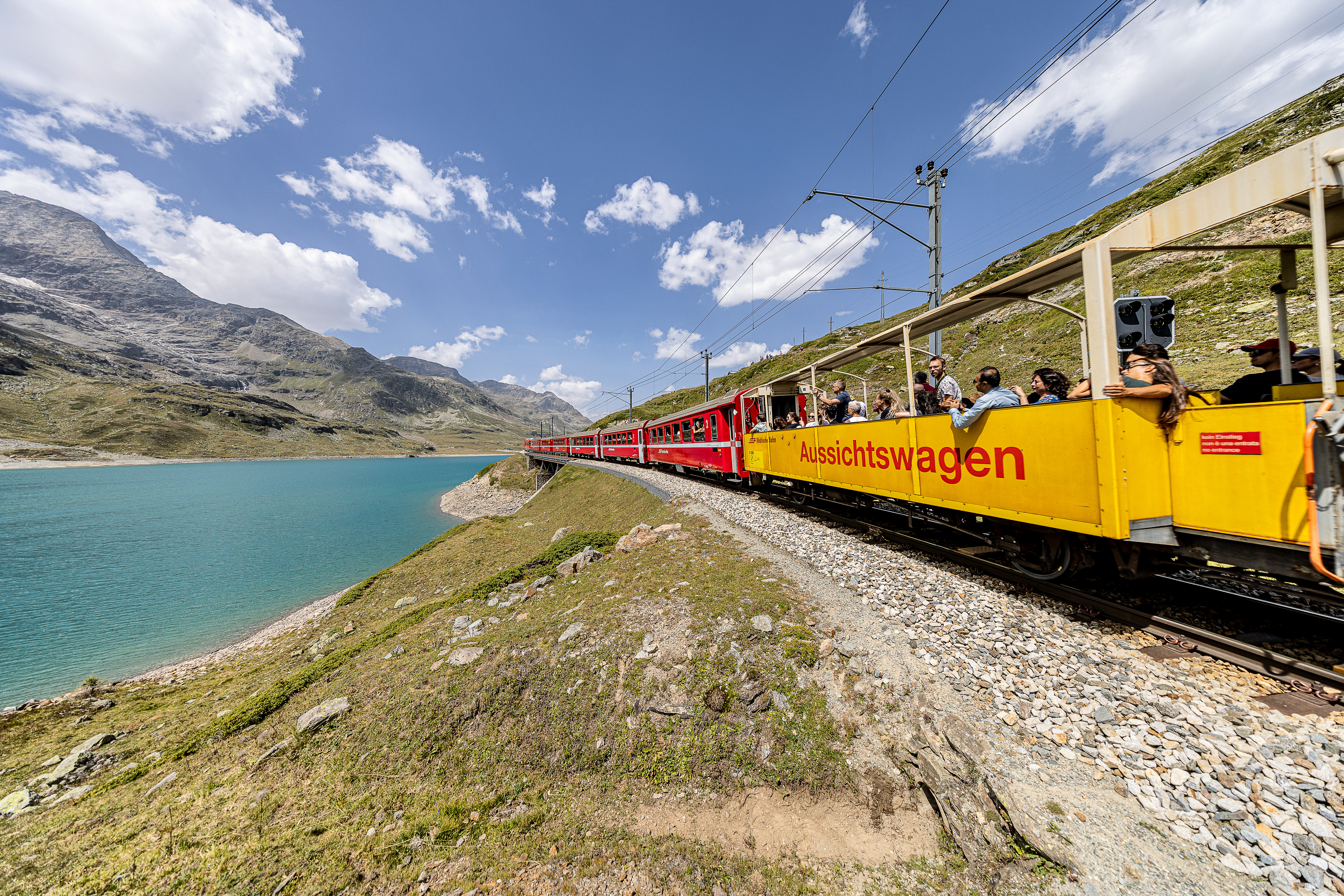 Ein offener Aussichtwagen der Rhätischen Bahn an einem Regionalzug beim Lago Bianco.