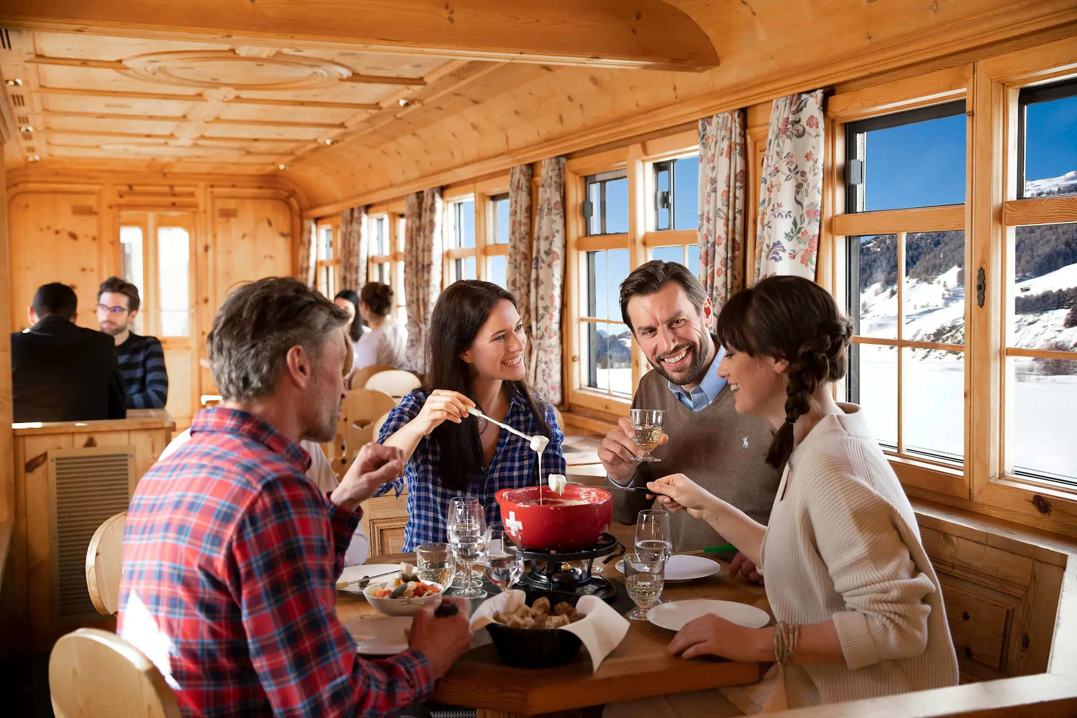 Vier Fahrgäste bedienen sich an einem Fondue im Stiva Retica