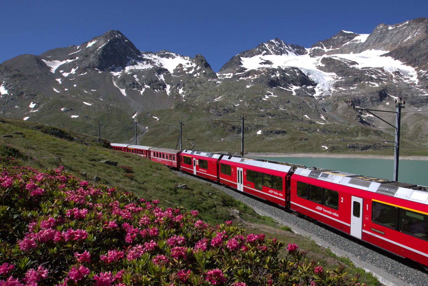 Ein Regionalzug fährt durch malerische Landschaft am Lago Bianco.