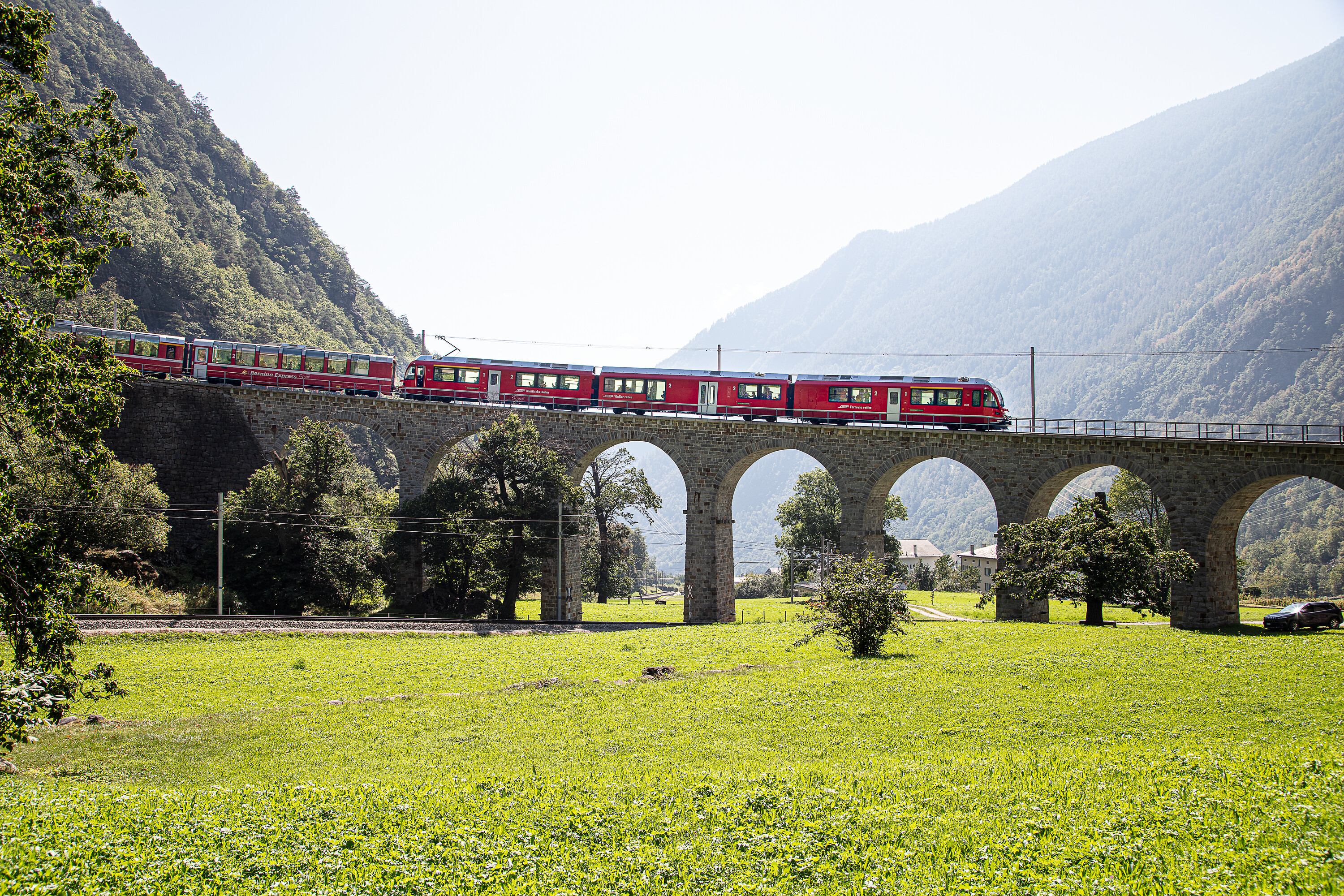 In tren cotschen sa chatta tranter auter en il viaduct da rudè a Brusio che s'integrescha en la cuntrada verda dal Puschlav.