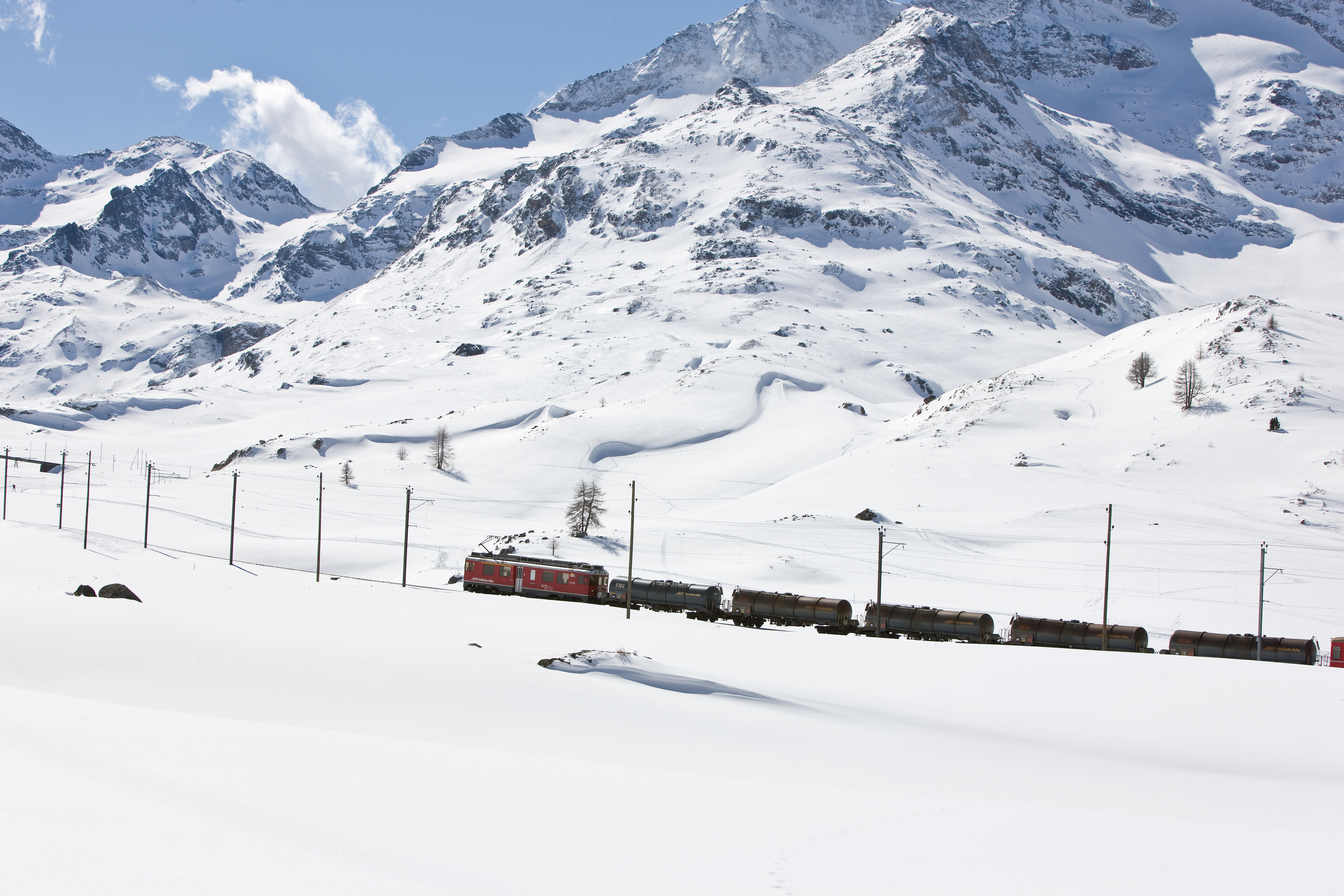 Ein Güterzug mit Mineralölkesselwagen fährt im Winter auf der Berninalinie