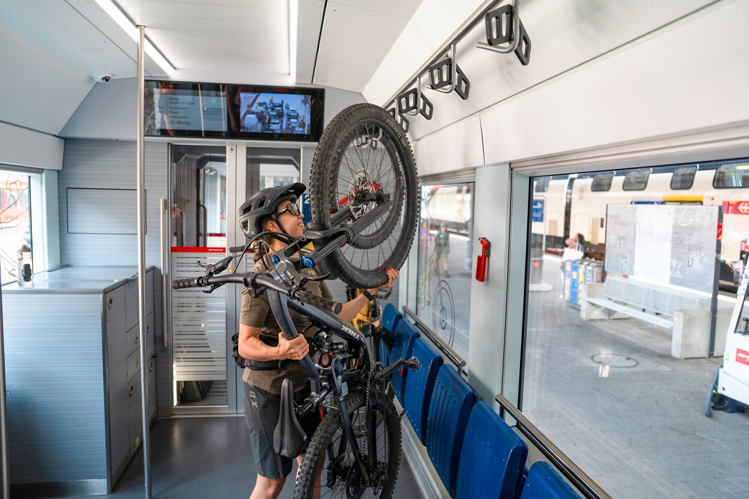 Eine Frau befestigt ihr Bike im RhB-Zug.
