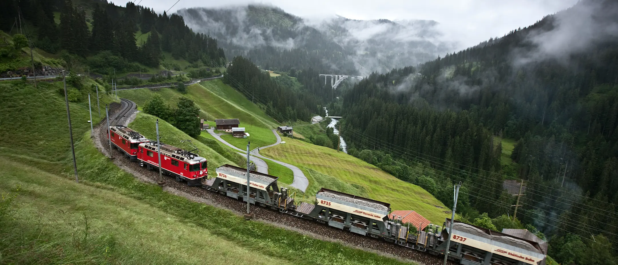Drei Schüttgutwagen der Rhätischen Bahn auf der Schiene