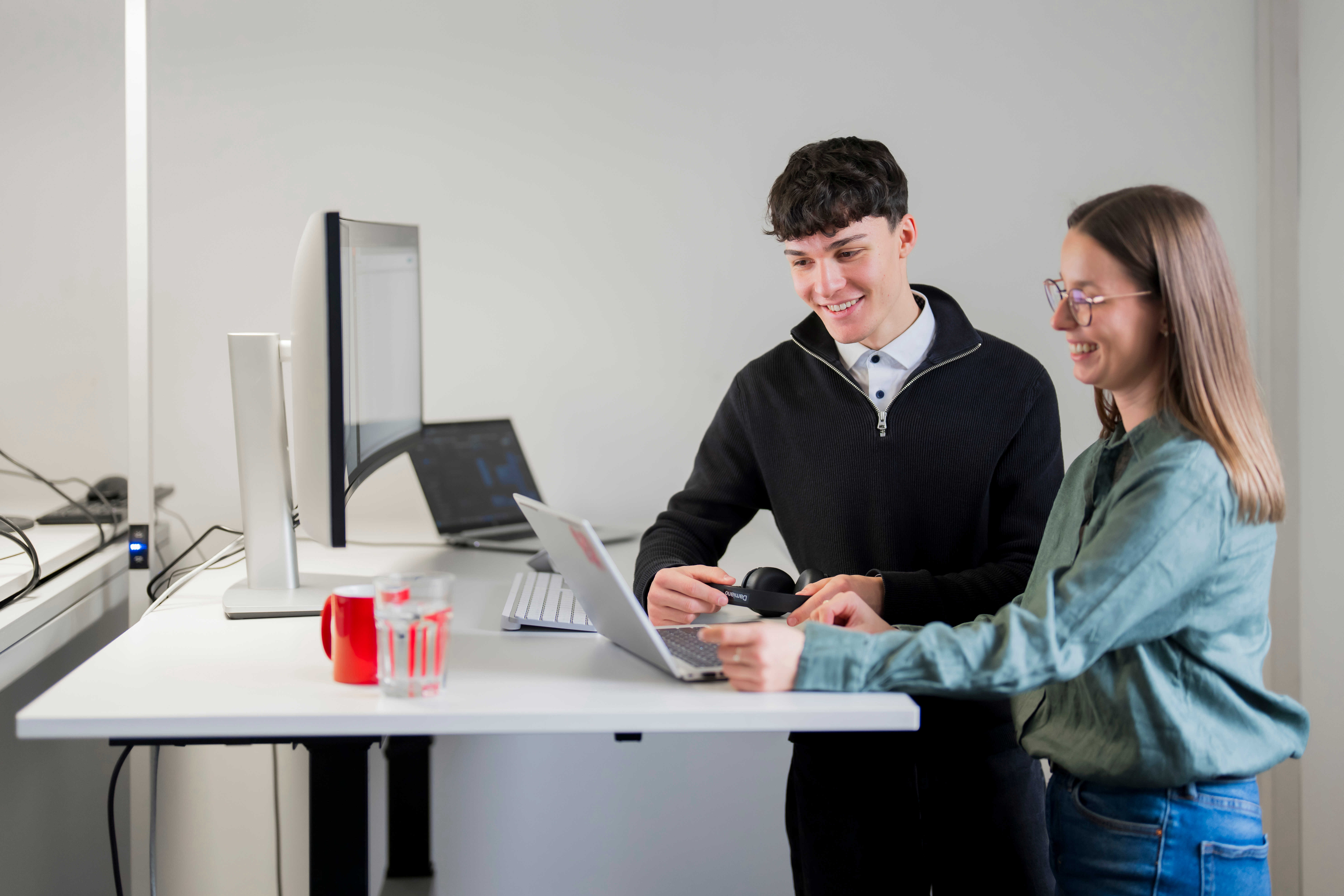 A male and a female colleague are discussing something on a laptop