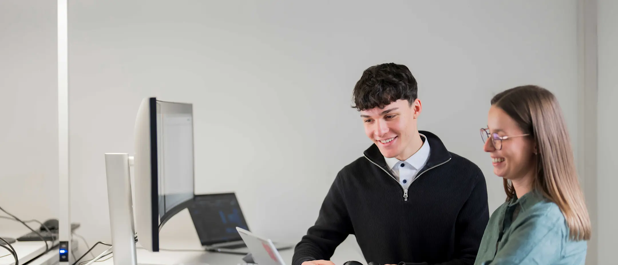 A male and a female colleague are discussing something on a laptop
