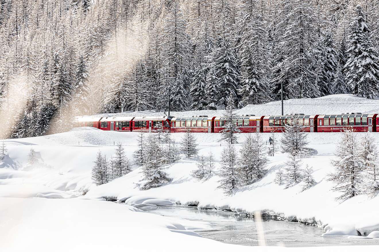 Der Bernina Express fährt durch eine tief verschneite Winterlandschaft bei Pontresina. 