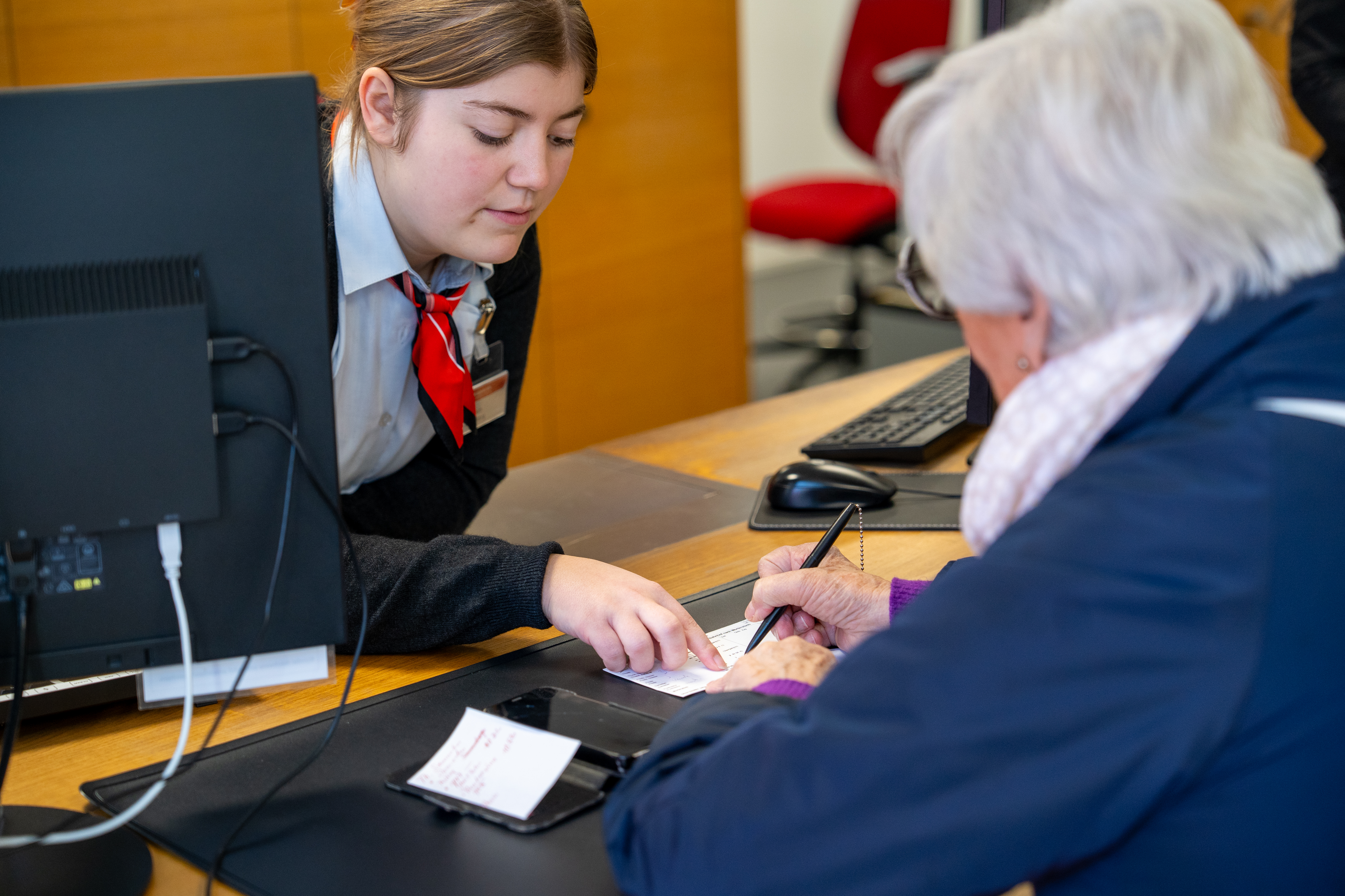 Lernende der Junior Station Thusis bedienen drei Kunden am Schalter.