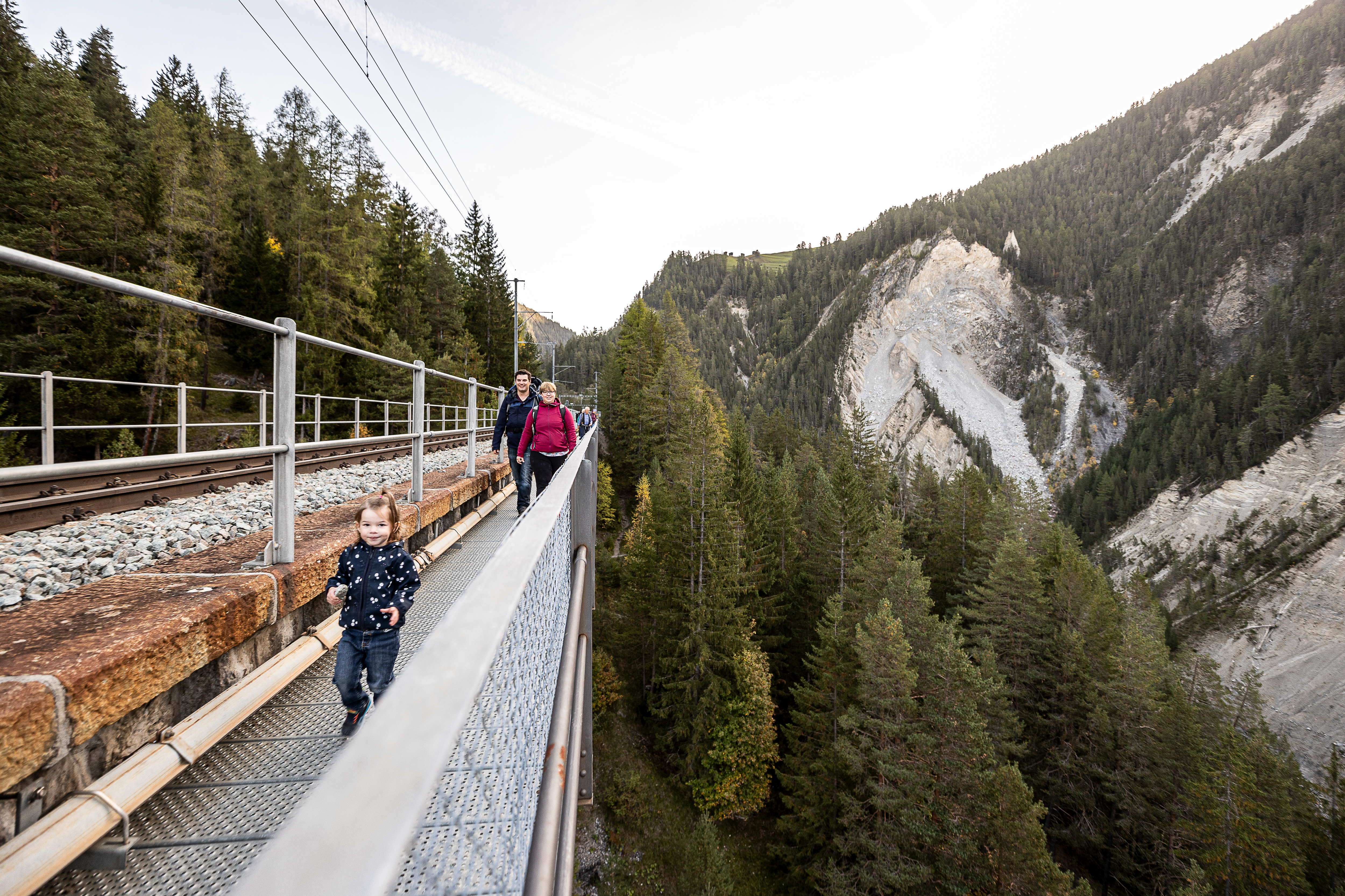 Der Fussgängersteg auf dem Wiesner Viadukt neben dem Gleisbett, eine Familie geht wandern