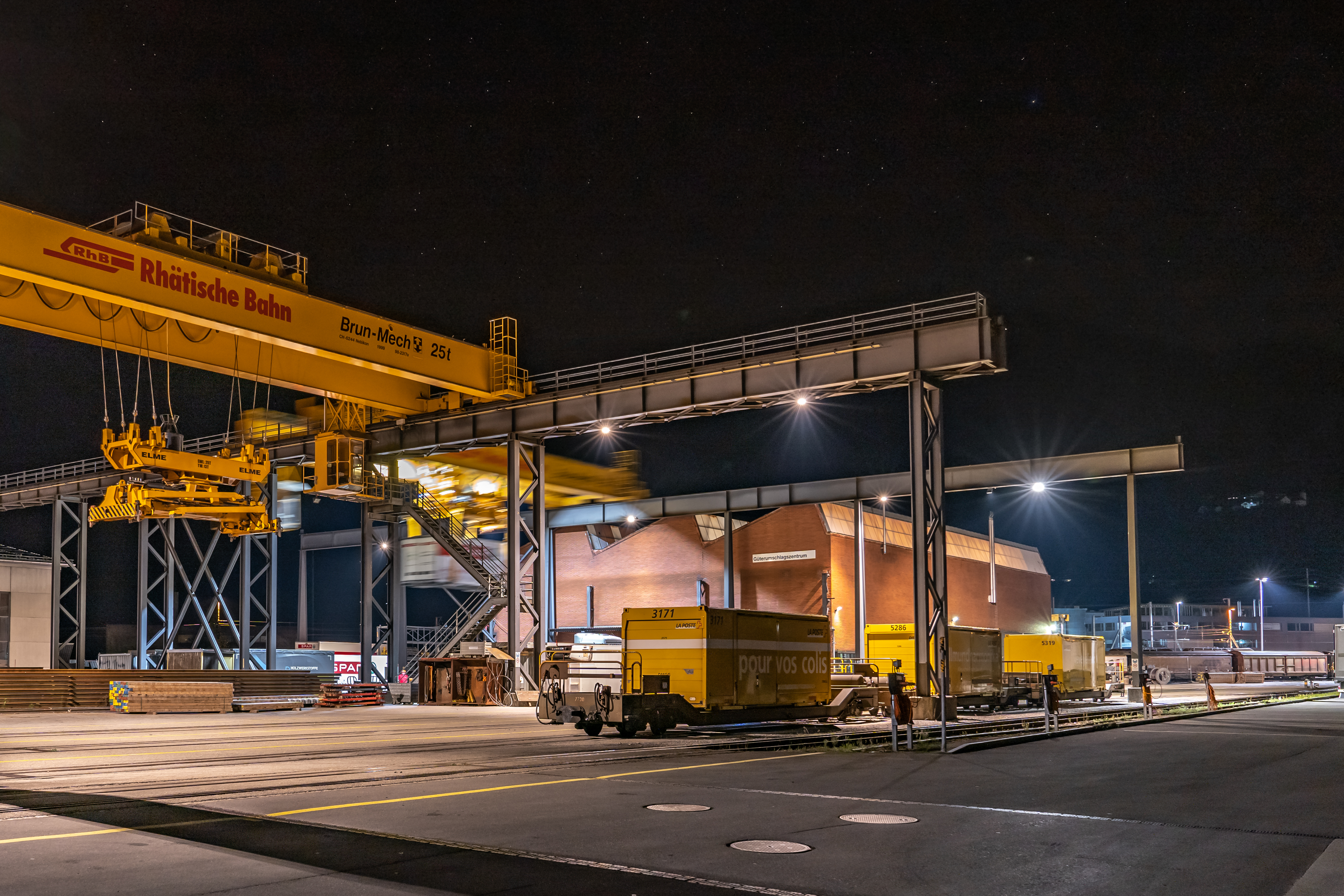 Das Güterumschlagszentrum Landquart der Rhätischen Bahn bei Nacht, ein Container wird auf einen LKW geladen