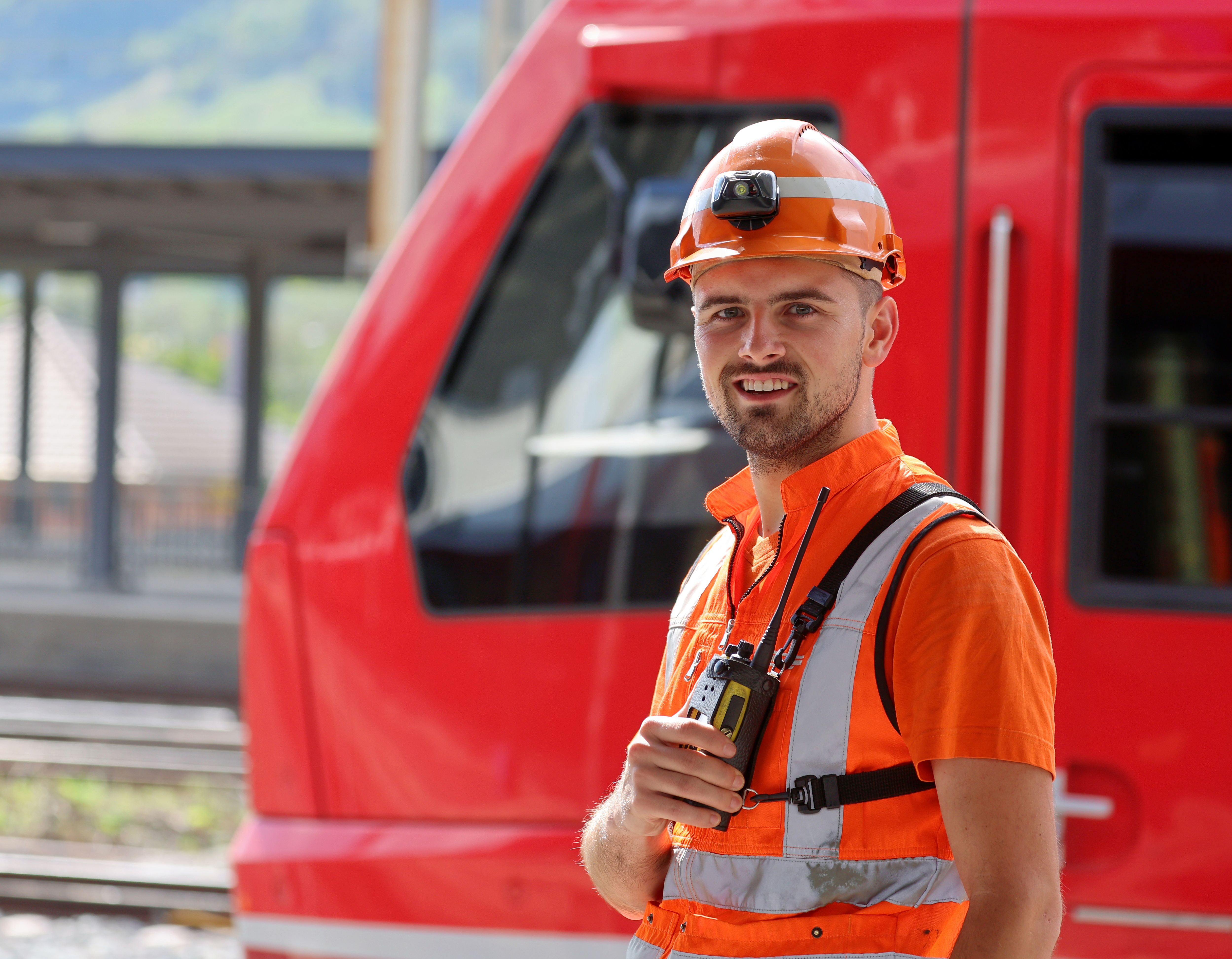 Employee with radio and headlamp in front of train