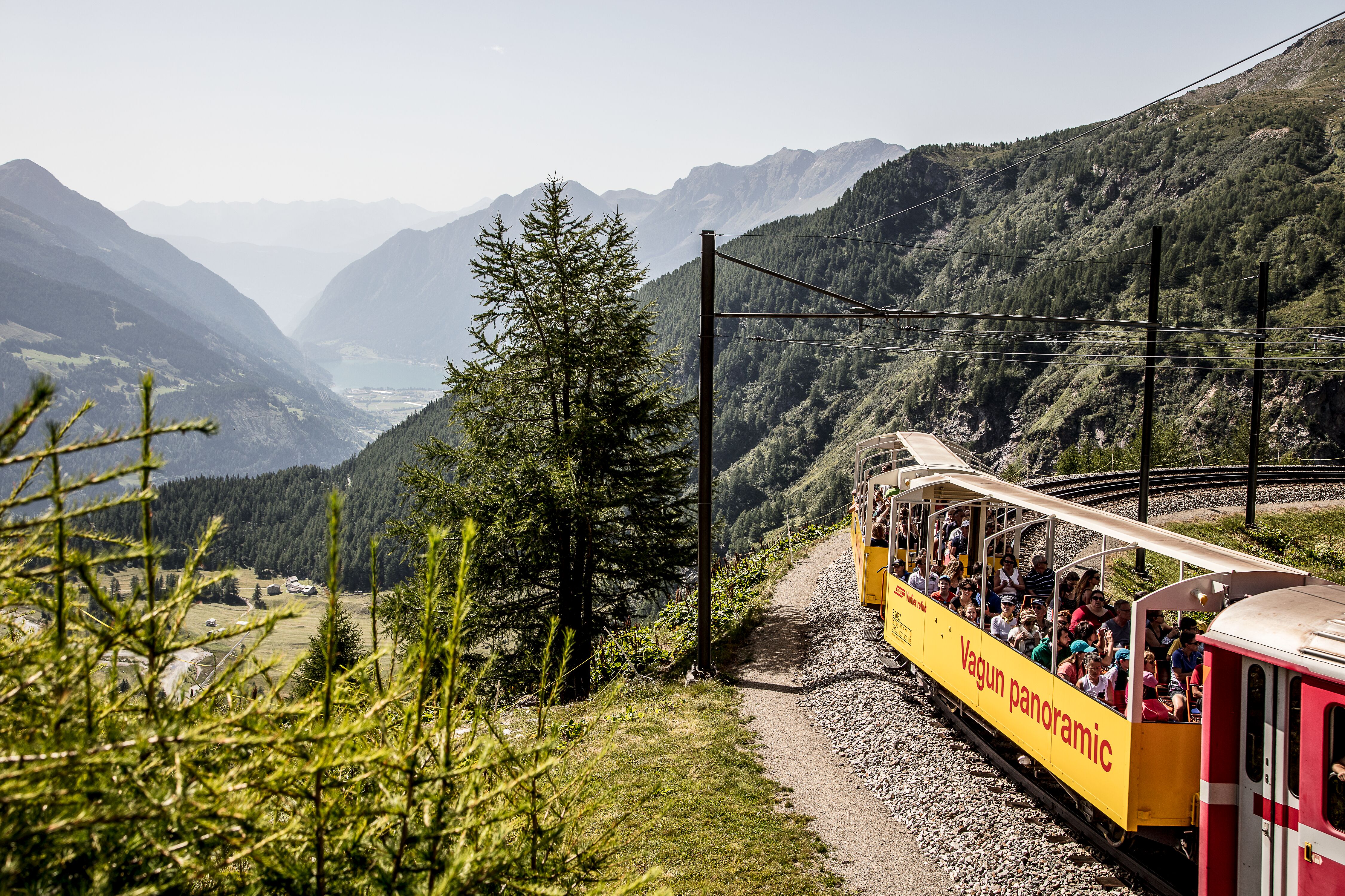 Gli ospiti ammirano il panorama dall'Alp Grüm a bordo di una carrozza panoramica aperta.