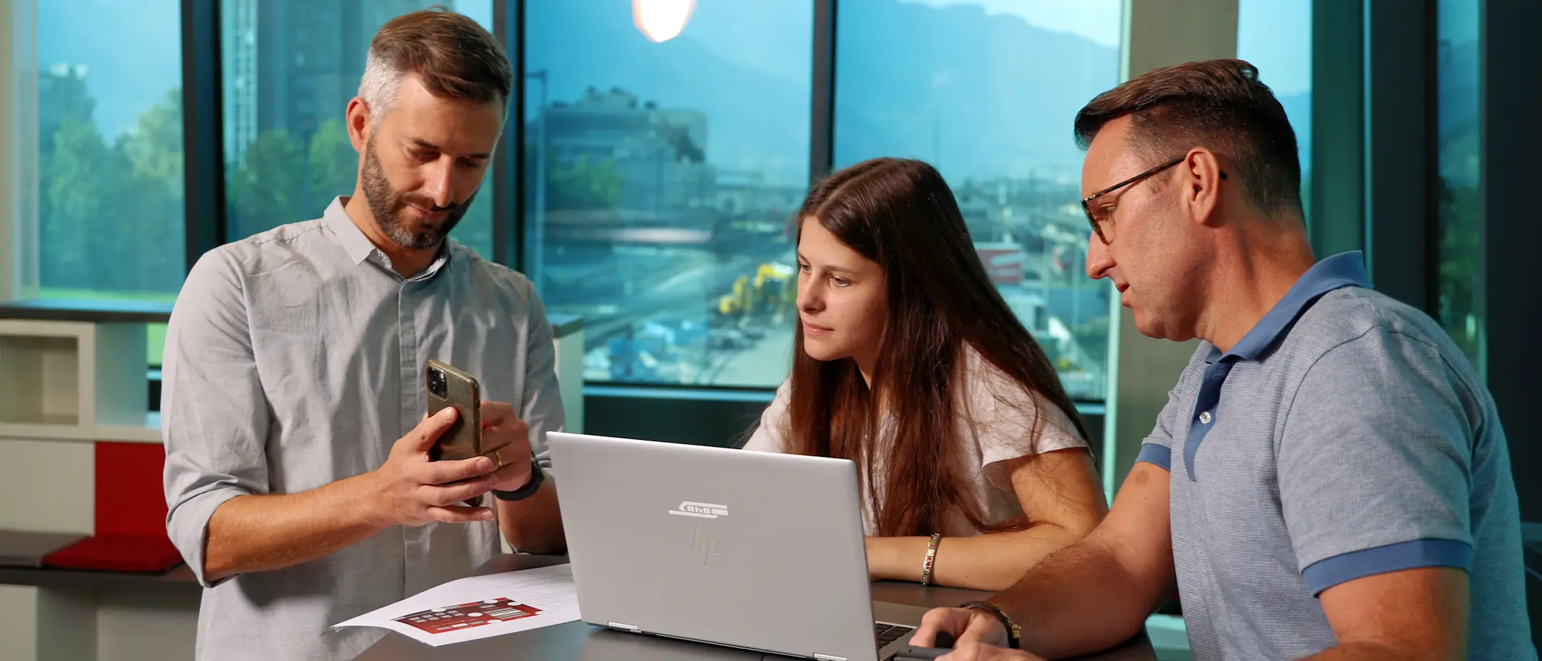 Ein Mitarbeitender erklärt auf dem Mobilephone eine Anwendung