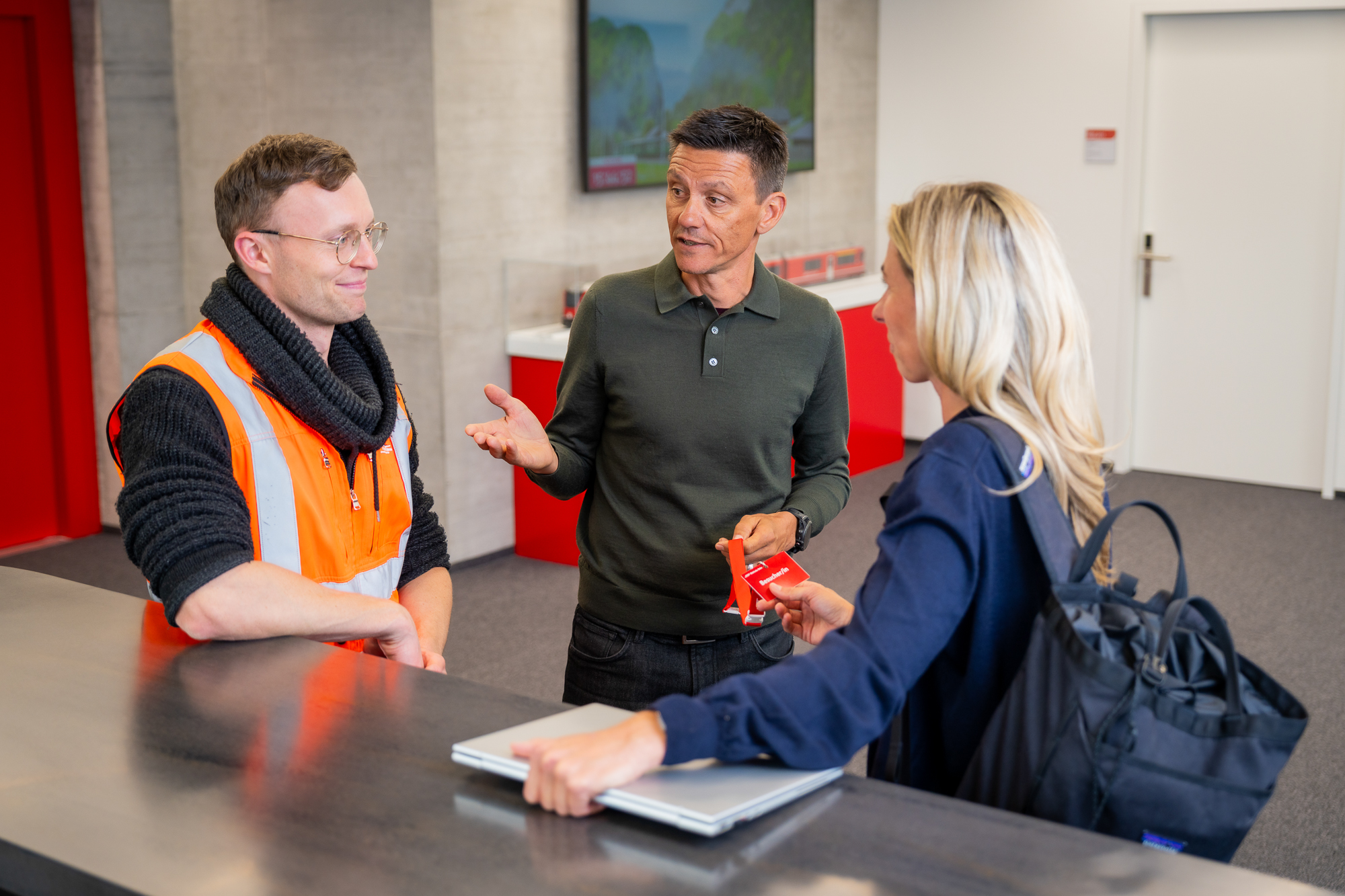 Drei Mitarbeitende stehen an einer Theke und sprechen miteinander