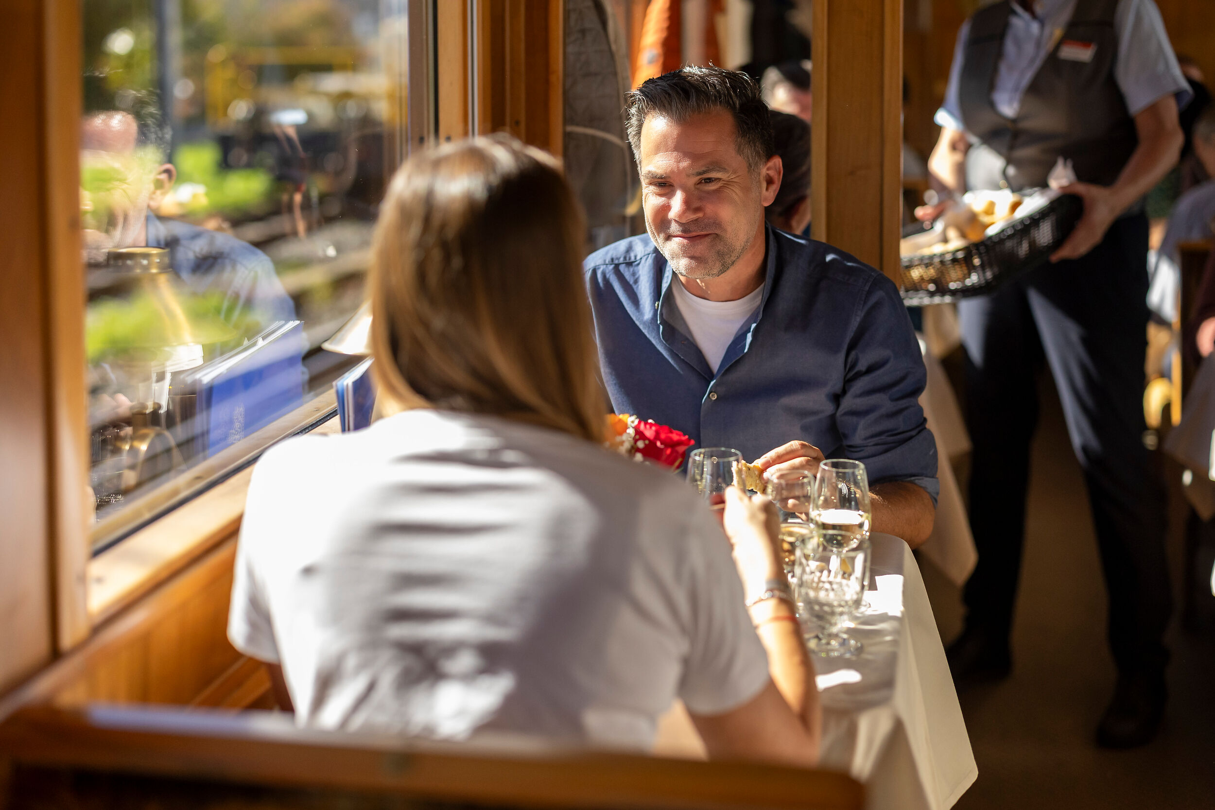 Zwei Personen sitzen im nostalgischen Speisewagen Gourmino am Tisch und unterhalten sich. 