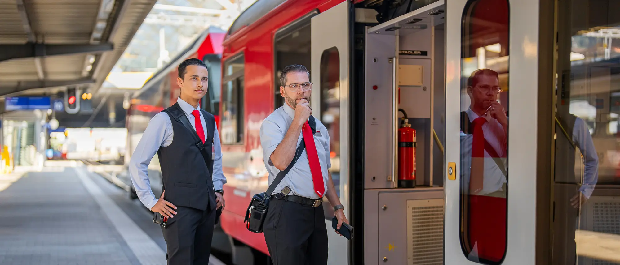 Ein Zugbegleiter erklärt einem Lernenden die Tätigkeit Abfahrtspfiff