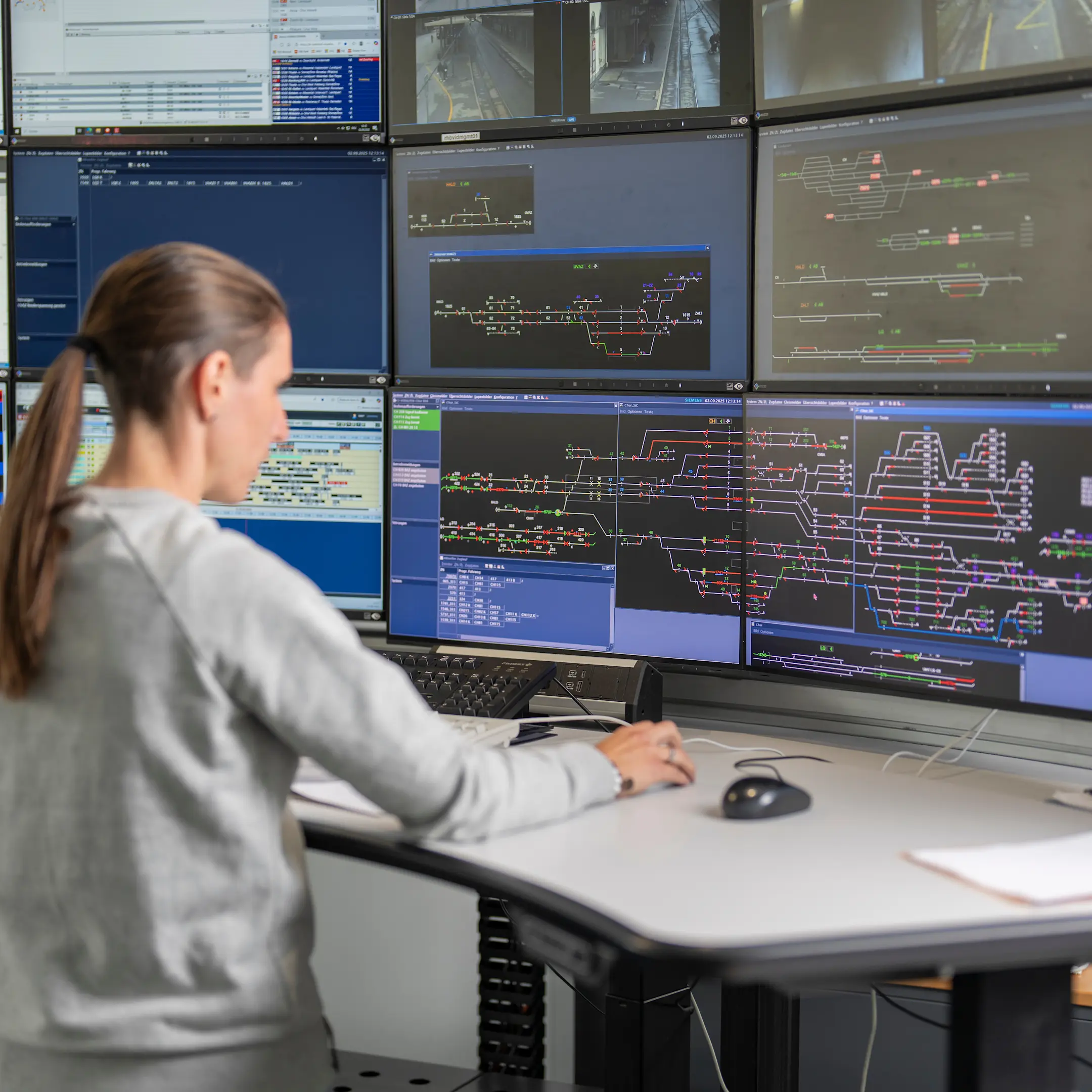Eine Zugverkehrsleiterin der RhB steht am Schreibtisch vor zahlreichen Monitoren