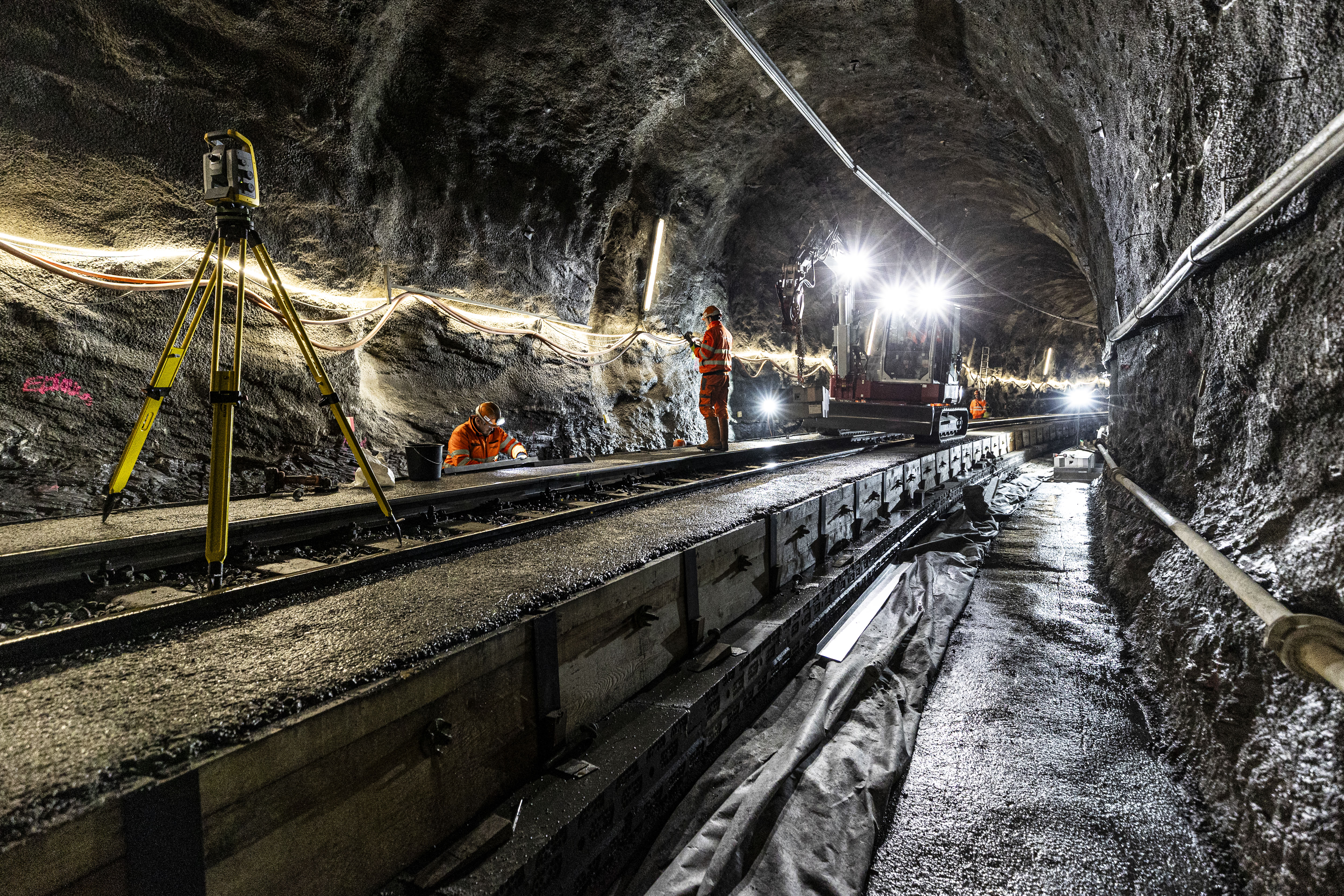Instandsetzungsarbeiten im Touatunnel zwischen Thusis-Preda. Zu sehen sind Arbeitskräfte, Vermessungsgeräte und Baumaschinen.