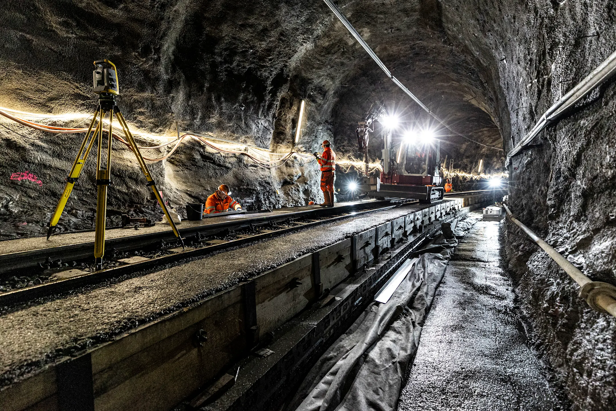 Instandsetzungsarbeiten im Touatunnel zwischen Thusis-Preda. Zu sehen sind Arbeitskräfte, Vermessungsgeräte und Baumaschinen.