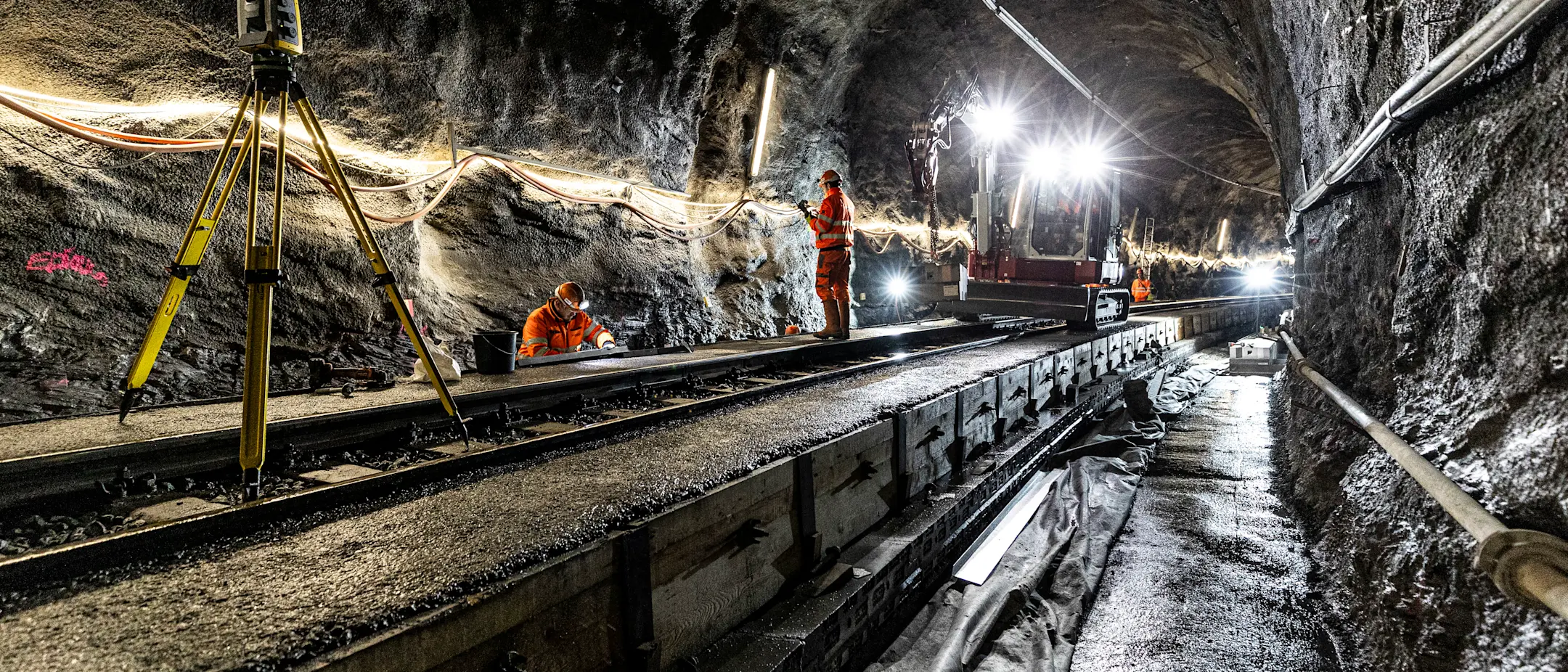 Instandsetzungsarbeiten im Touatunnel zwischen Thusis-Preda. Zu sehen sind Arbeitskräfte, Vermessungsgeräte und Baumaschinen.