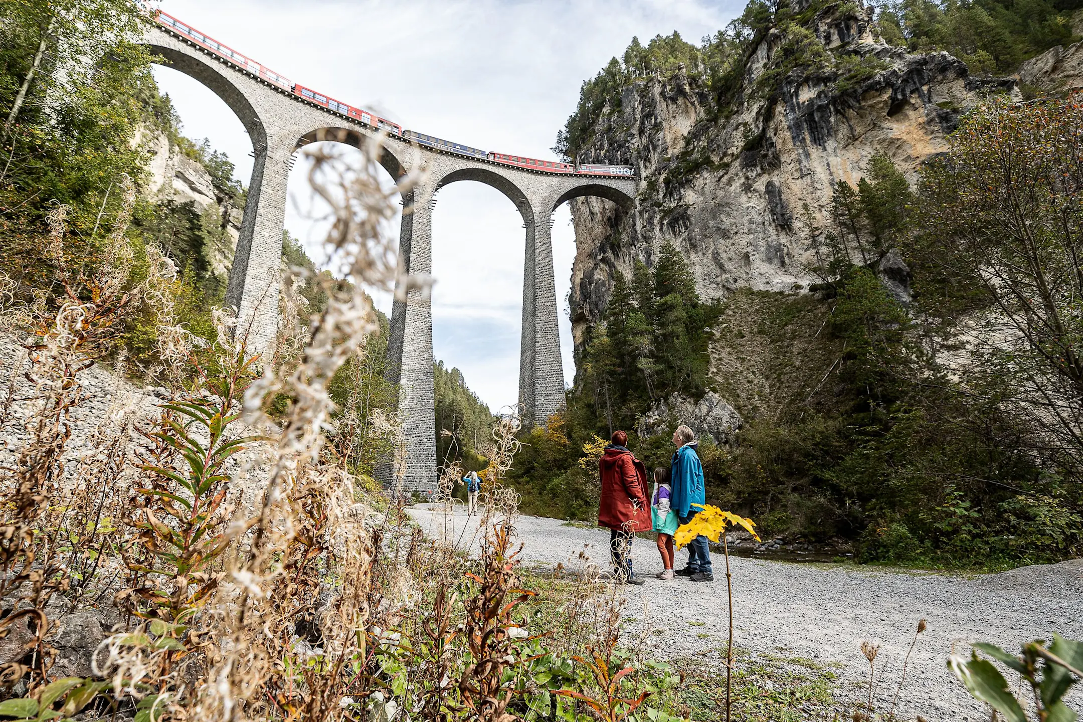 Eine Familie steht auf dem Viaduktplatz und schaut von unten auf den Landwasserviadukt.