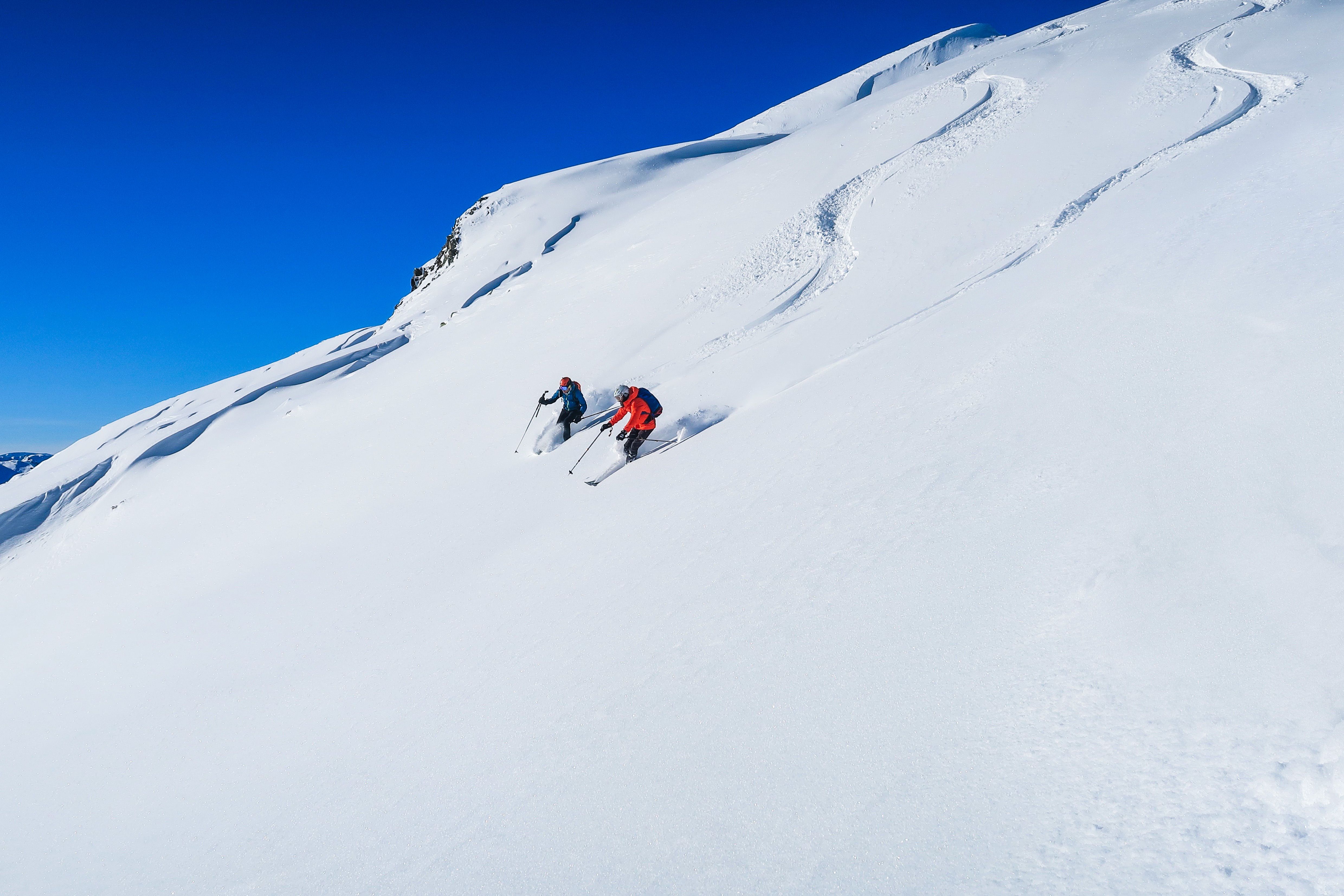 Zwei Skifahrer fahren abseits der Piste im Pulverschnee