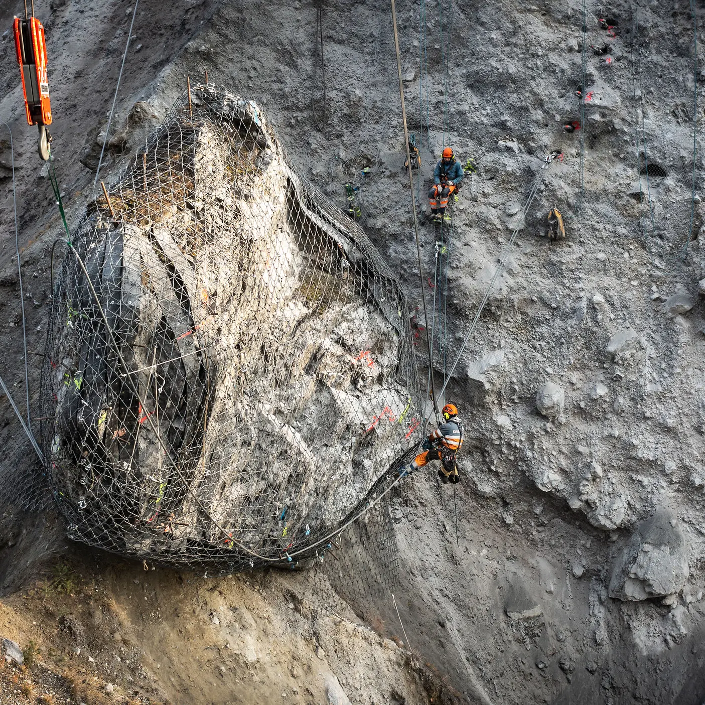 Ein riesiger Felsblock wird in der Rheinschlucht mit Drahtseilen am Berg gesichert.