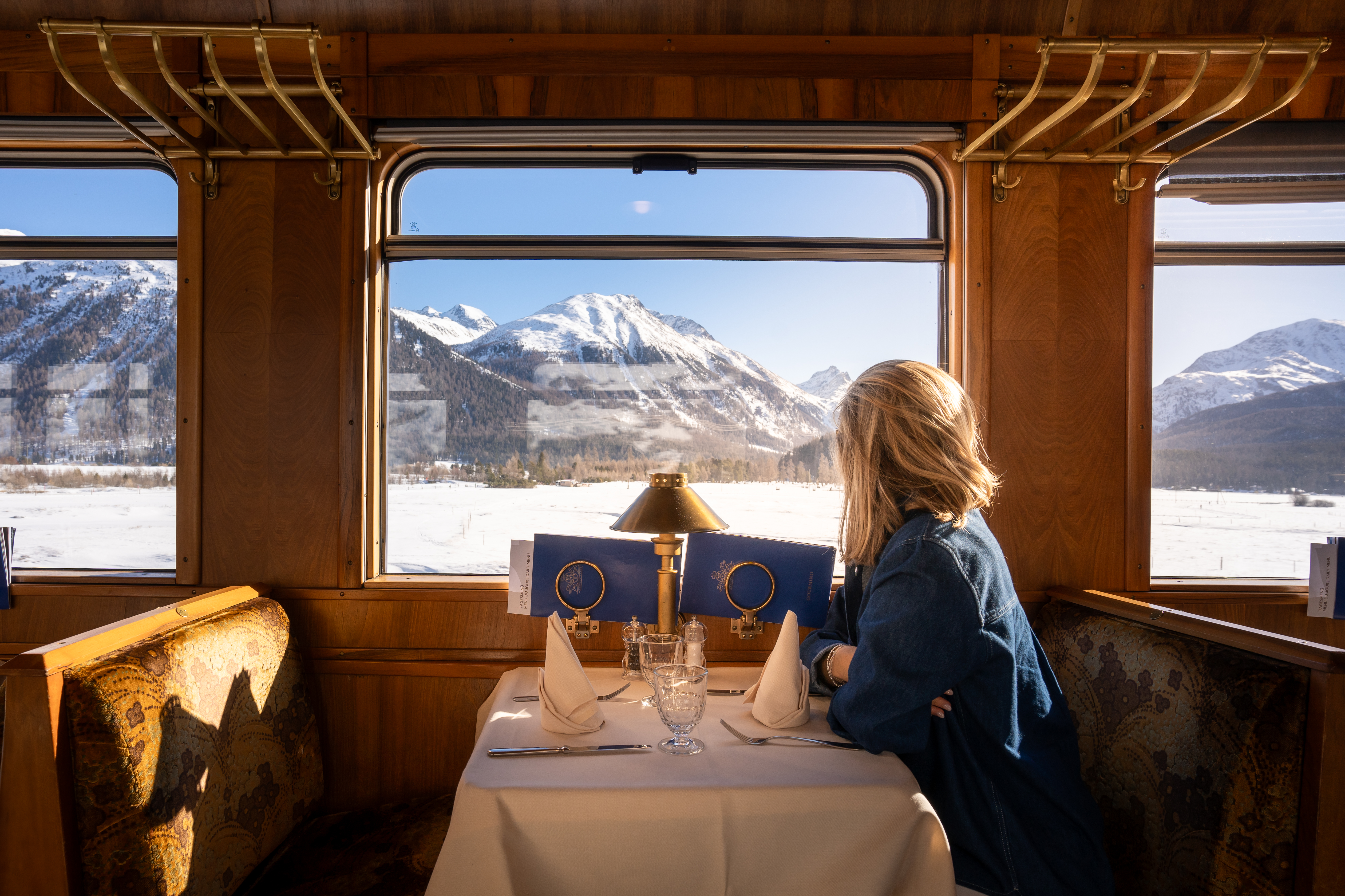 Eine Person im Speisewagen vor dem Alpenpanorama