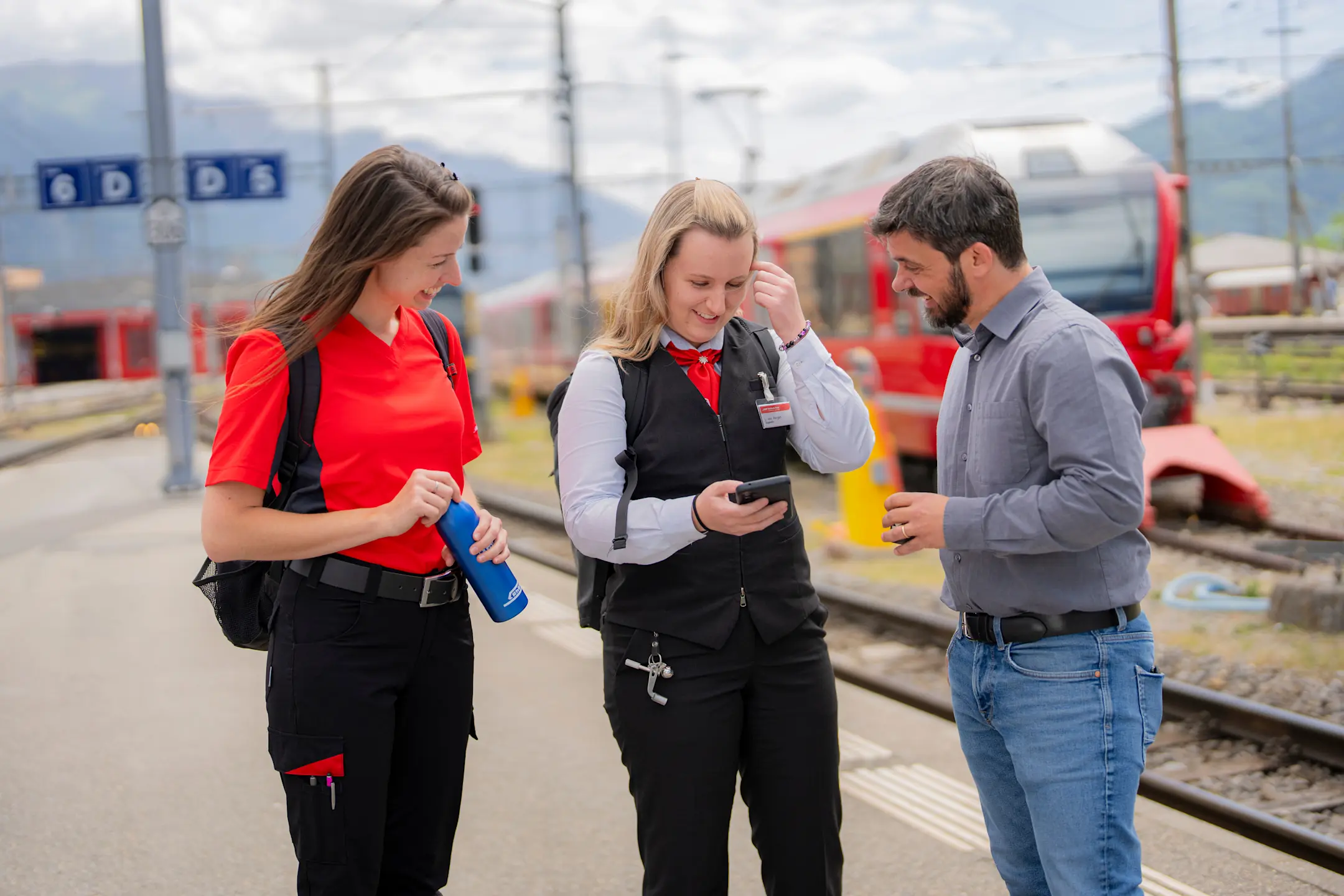 Zugbegleiter Lokführerin und Bürolist mit Mobiltelefon etwas am Besprechen auf Perron
