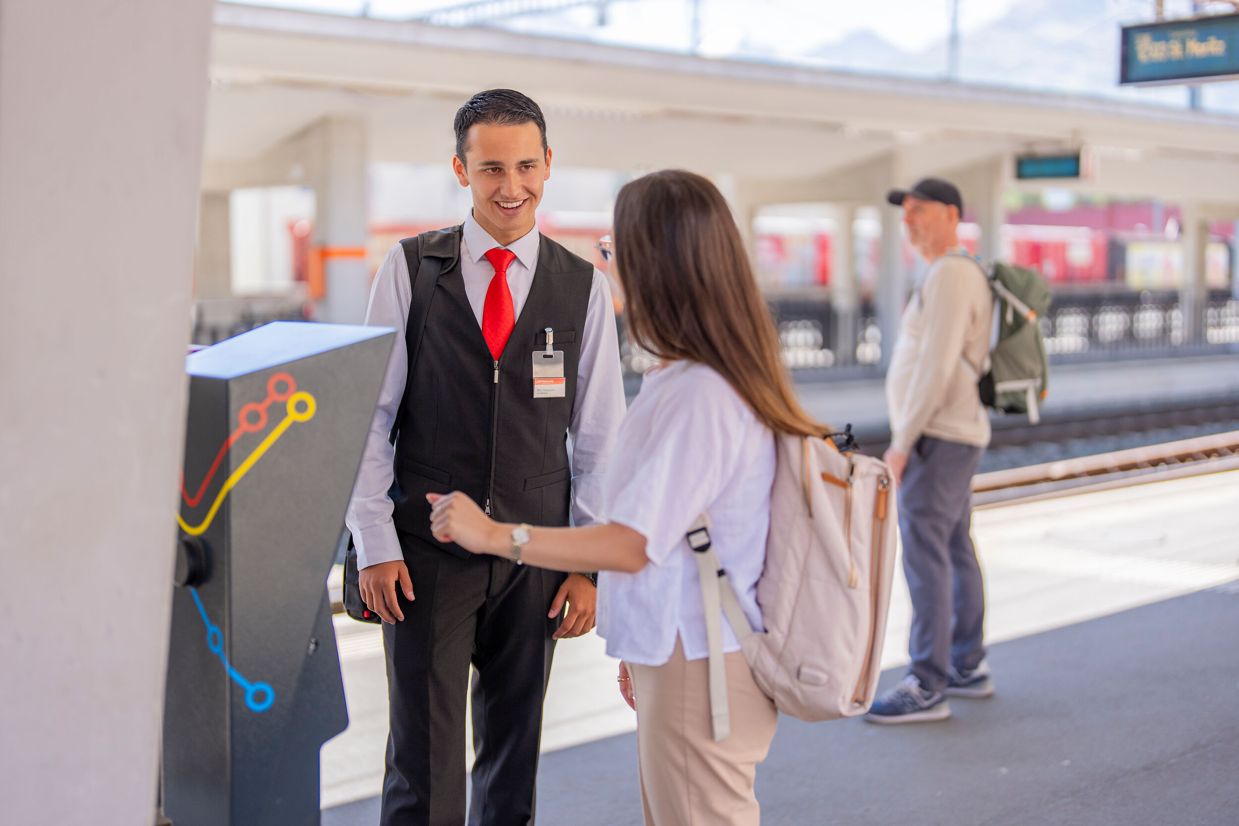 An RhB train guard talking to a passenger at the station.