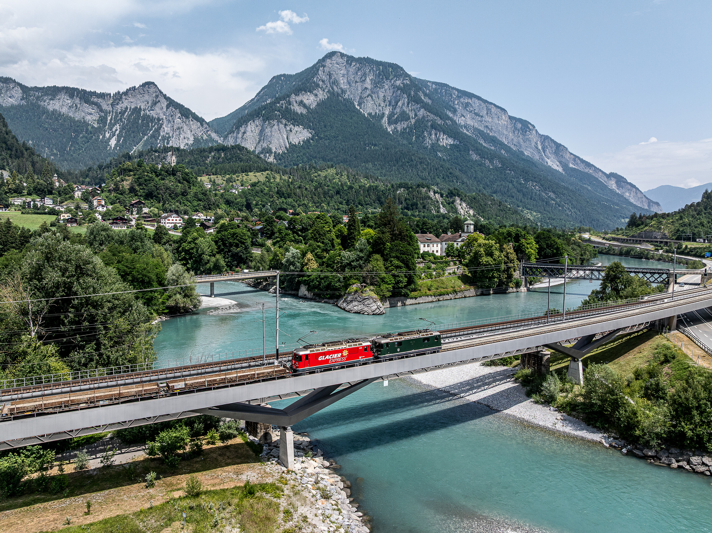 The Ge 4/4 II 623 locomotives in Glacier Express design and Ge 4/4 II 611 on the Hinterrhein Bridge in Reichenau-Tamins.