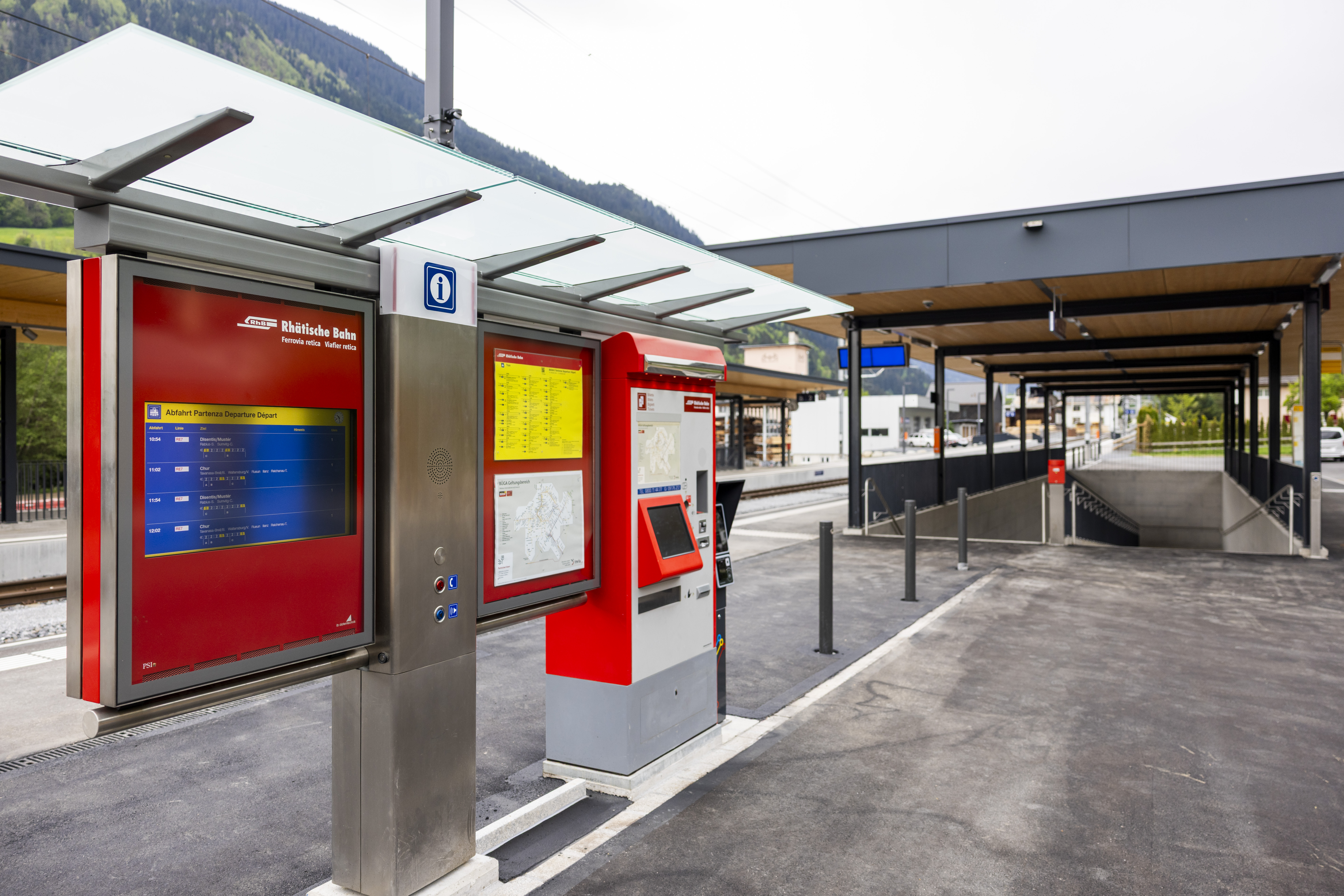 Billettautomat und Informationssystem der Rhätischen Bahn am Bahnhof Trun – modern, überdacht und gut erreichbar.