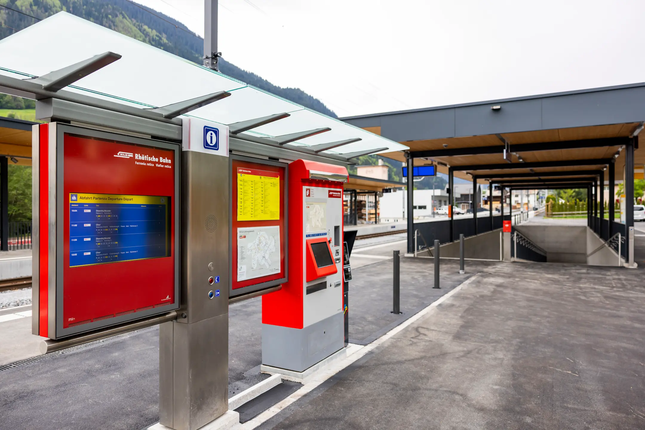Billettautomat und Informationssystem der Rhätischen Bahn am Bahnhof Trun – modern, überdacht und gut erreichbar.
