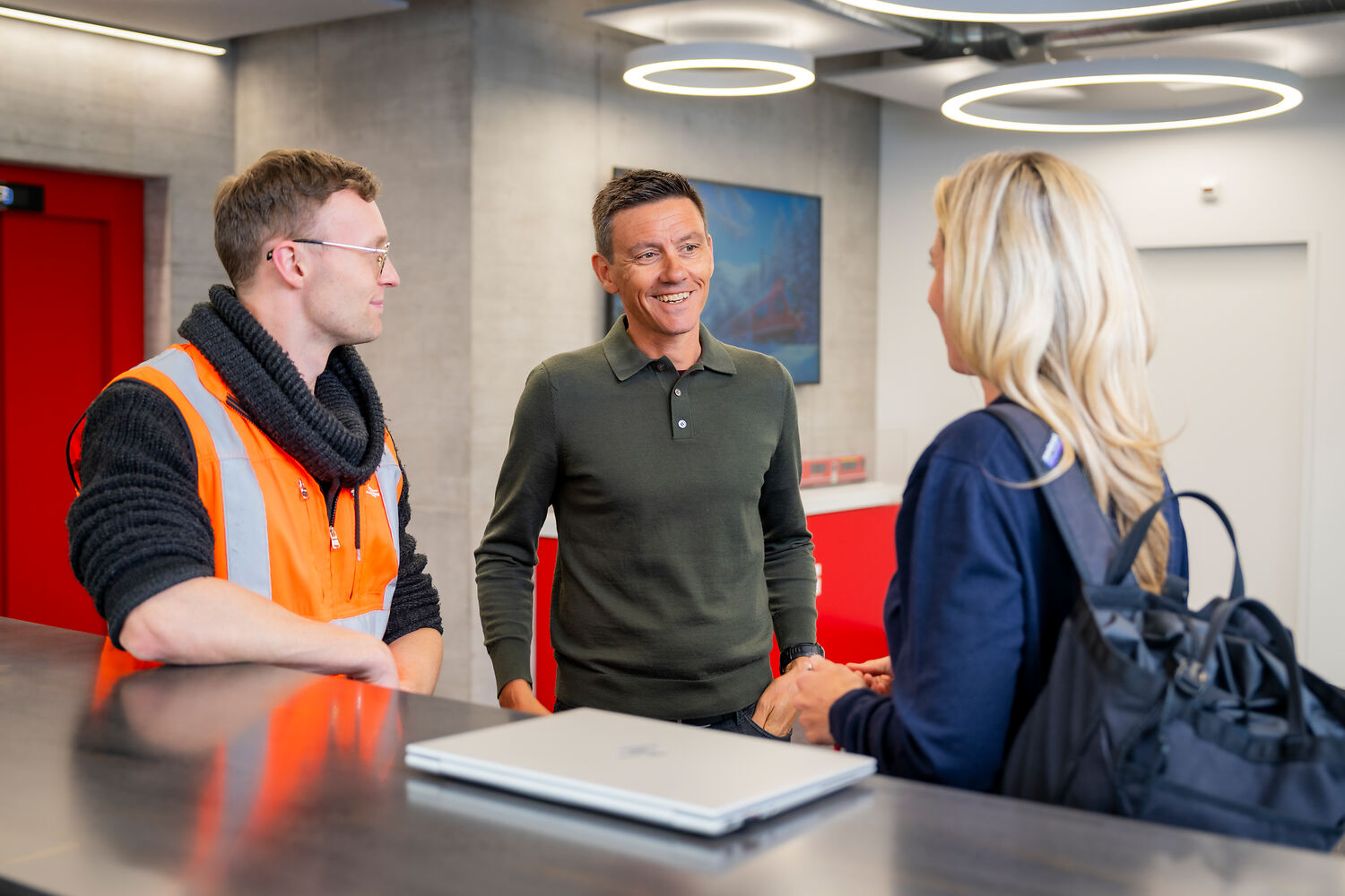 Employees talking with laptop and vest