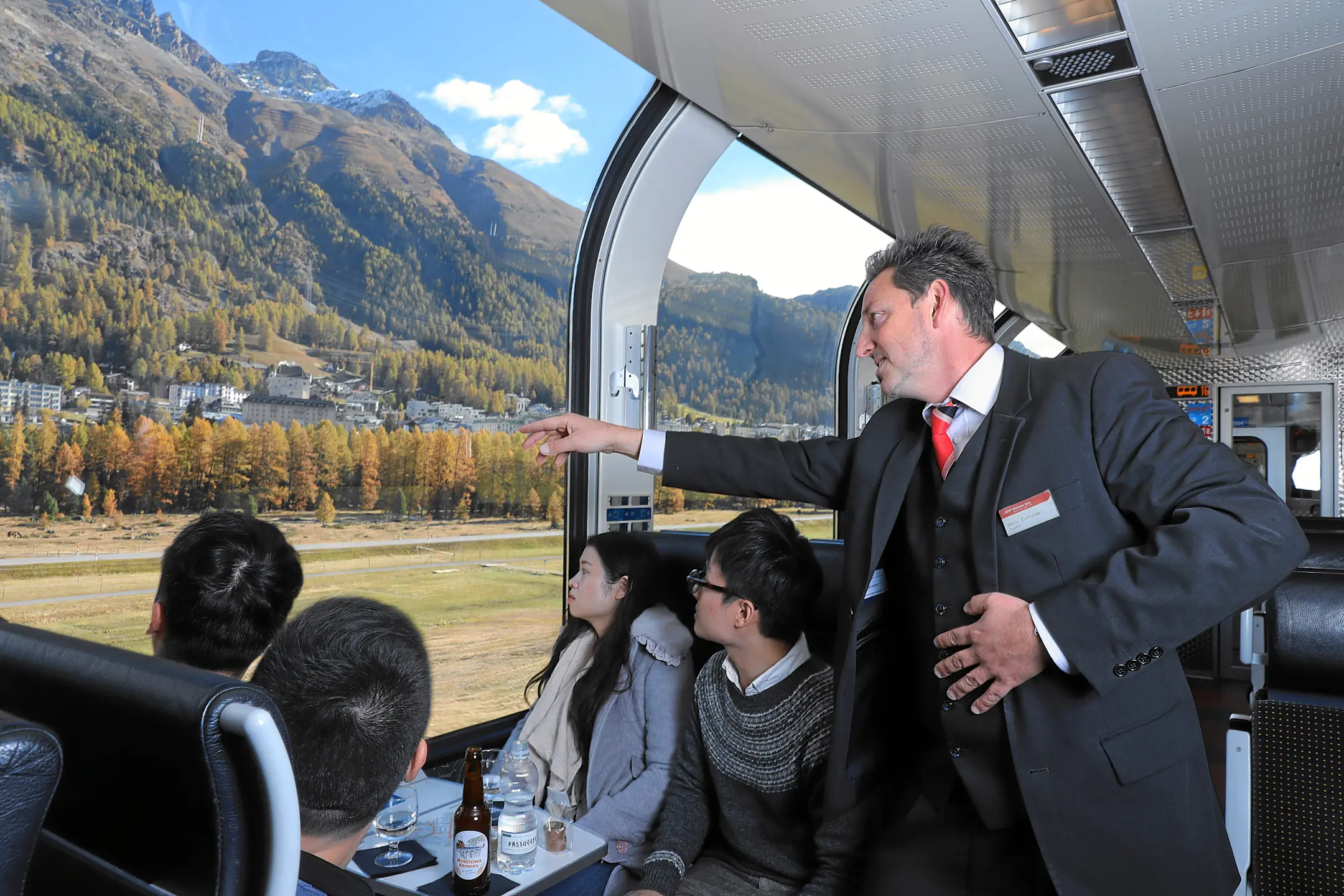 Ein Zugbegleiter der RhB zeigt Gästen im Panoramazug die Landschaft