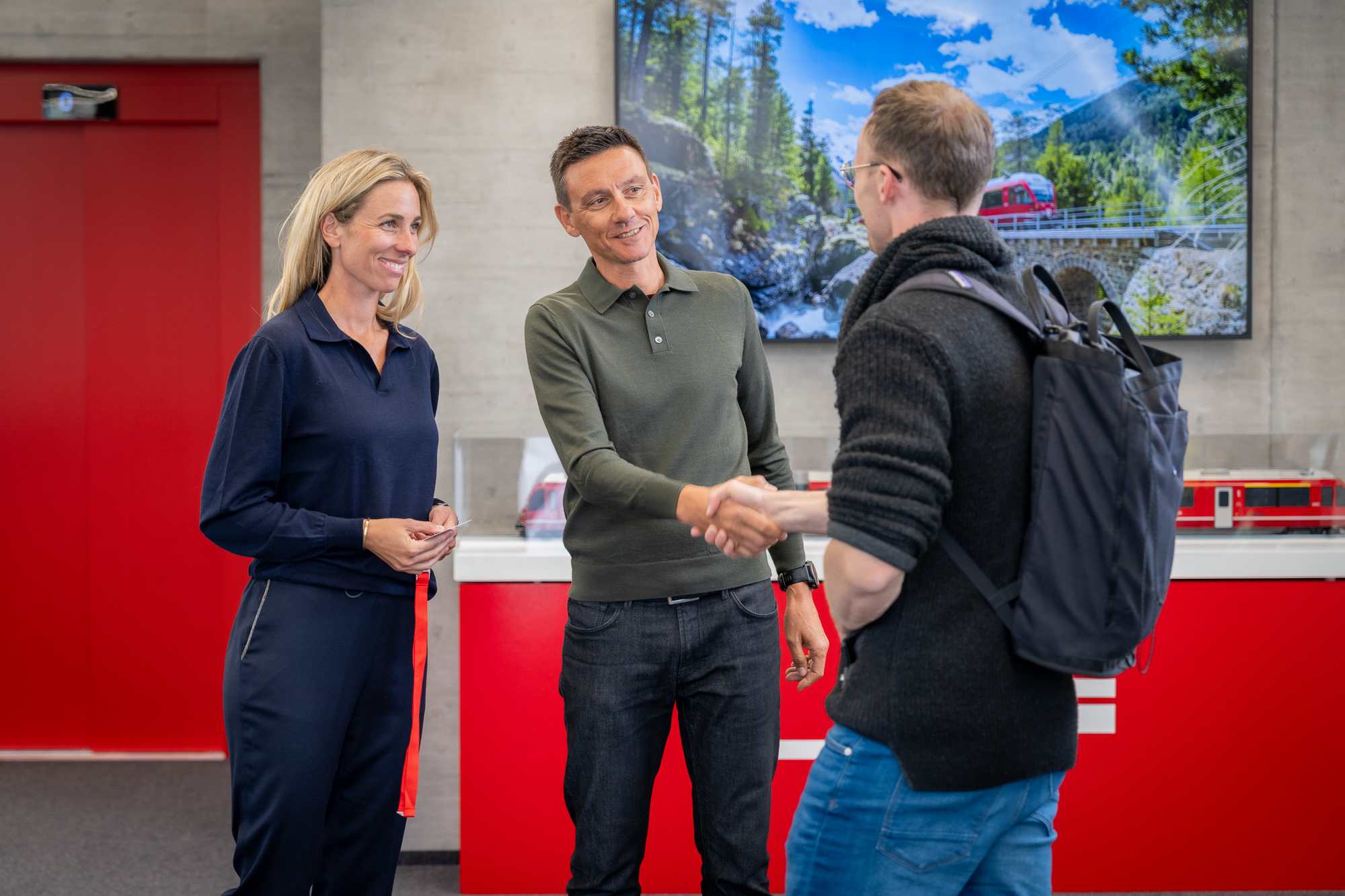 Ein Bewerbender wird von 2 Mitarbeitenden im Foyer begrüsst