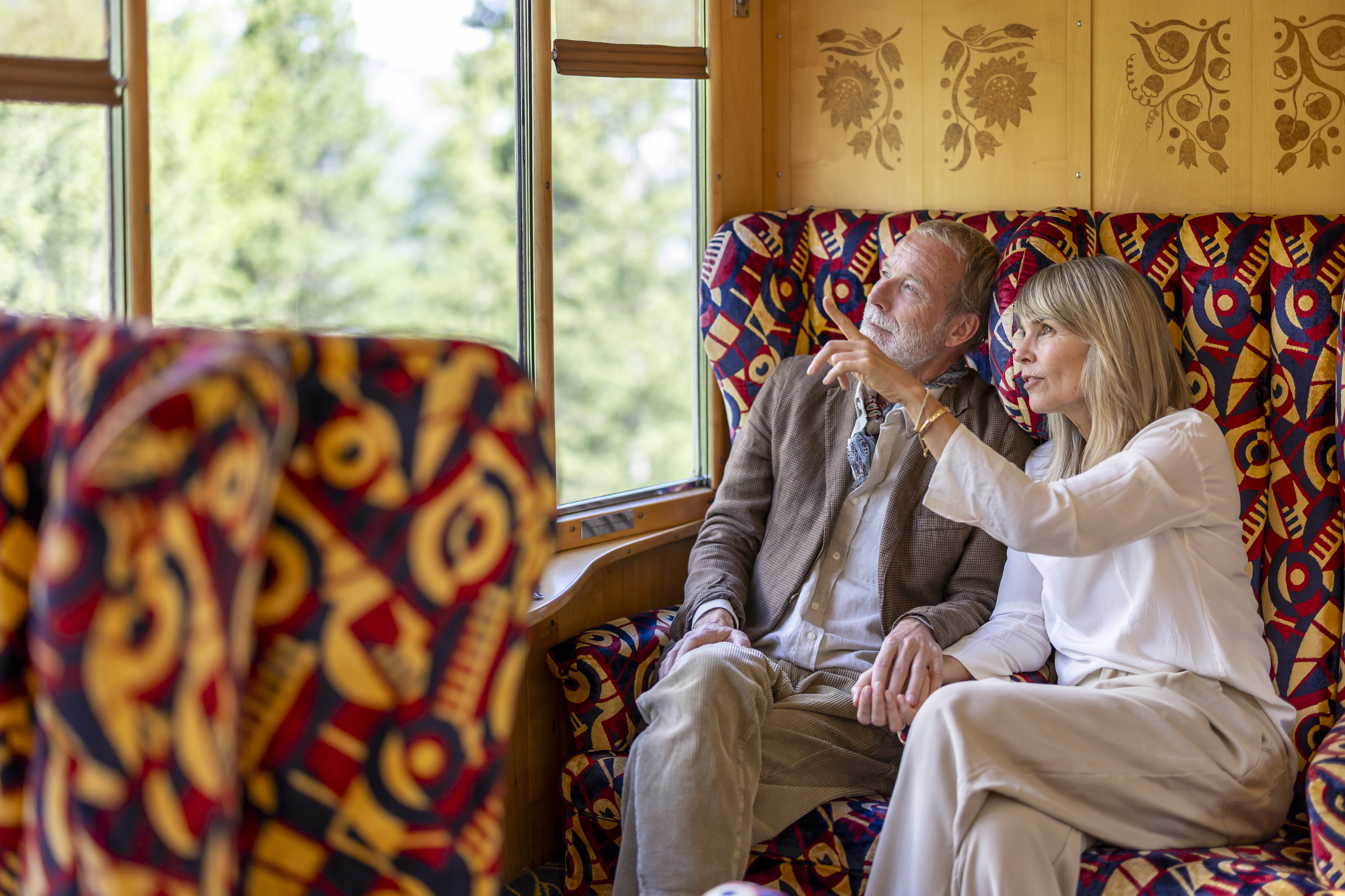 Zwei Personen sitzen im Pullman-Wagen und schauen durch die Fenster nach draussen. 