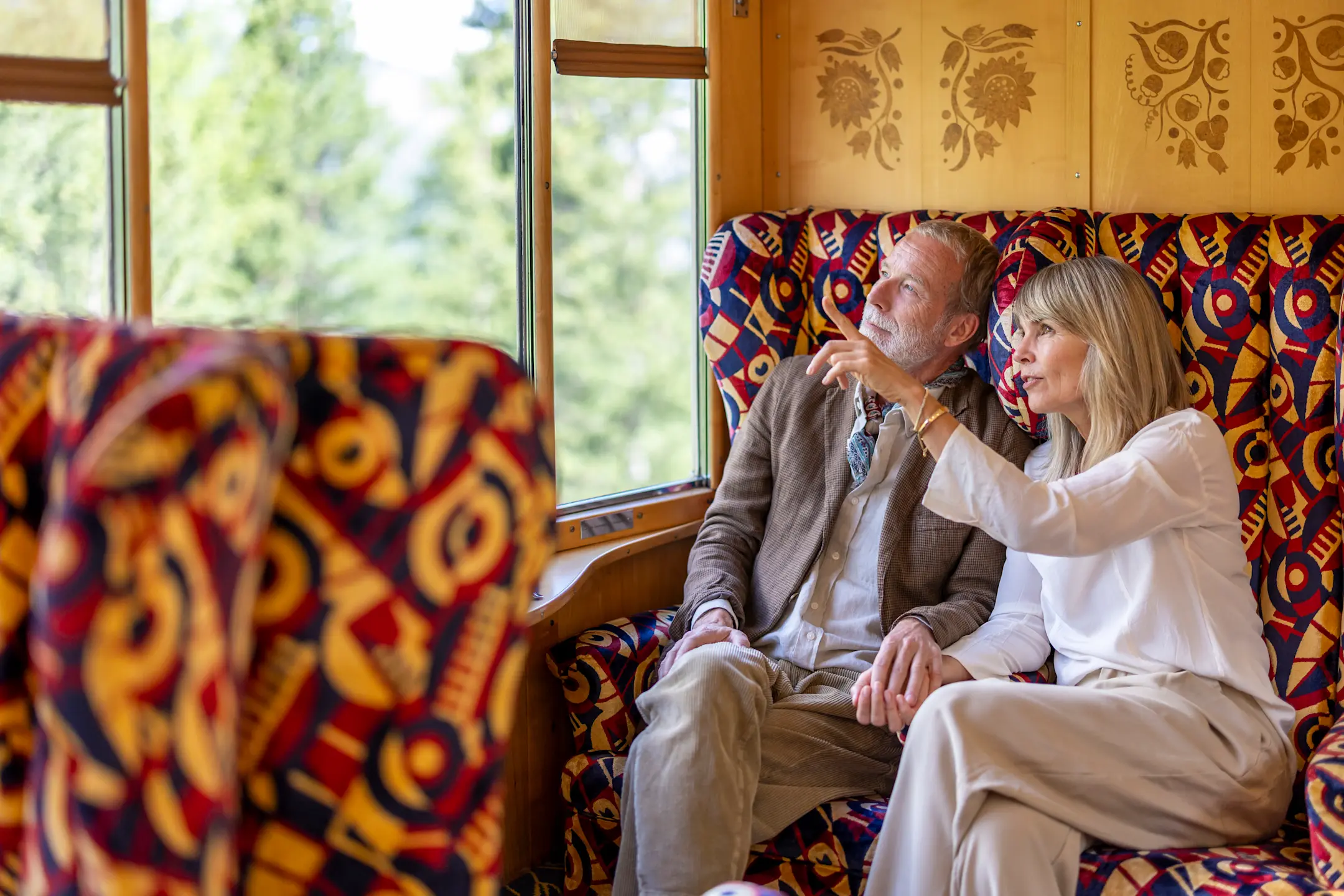 Zwei Personen sitzen im Pullman-Wagen und schauen durch die Fenster nach draussen.