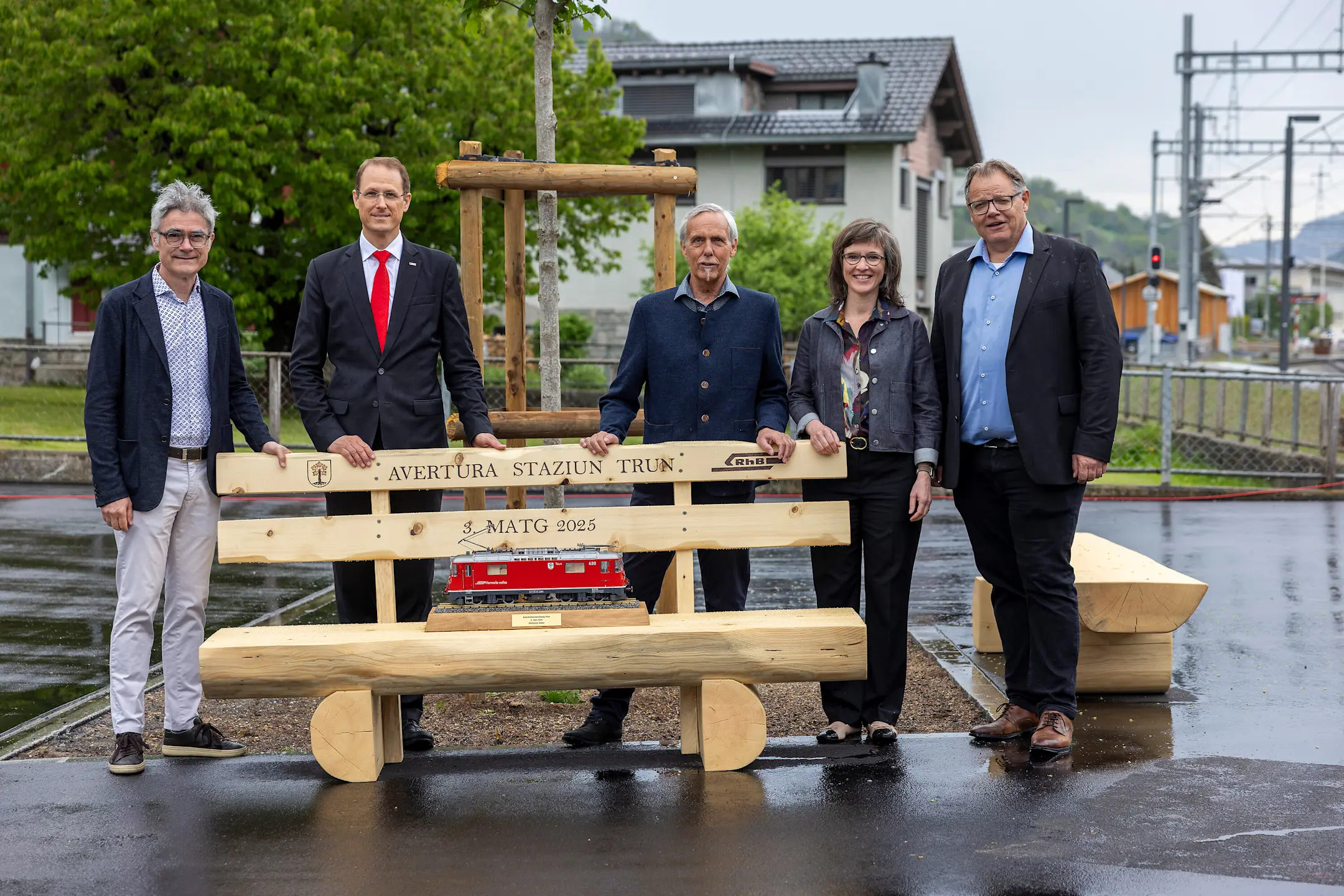 Mario Cavigelli, Renato Fasciati, Dumeni Tomaschett, Carmelia Maissen und Christian Florin  stehen hinter einer Sitzbank.