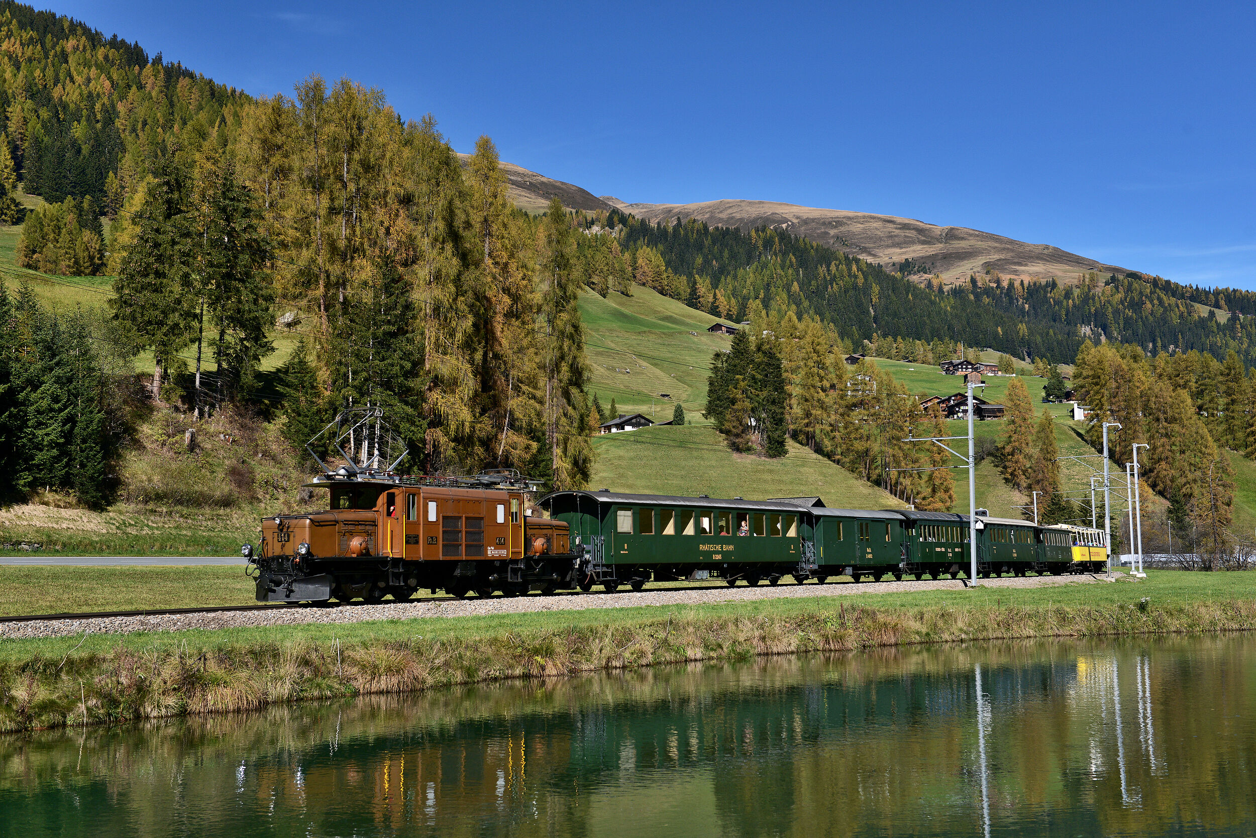 Die Kultlokomotive «Krokodil» der Rhätischen Bahn zieht historische Wagen durch die sommerliche Landschaft bei Davos. 