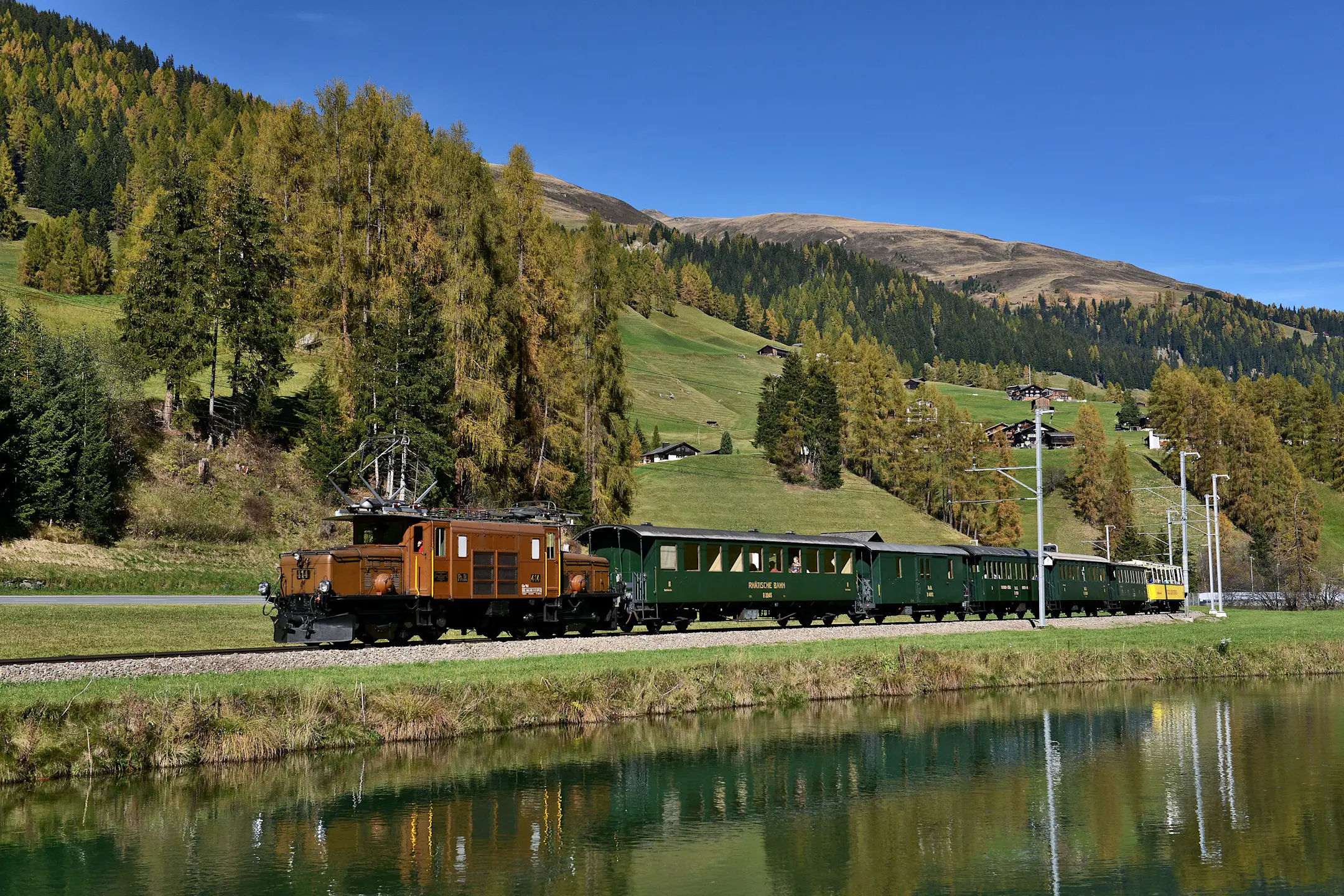 Die Kultlokomotive «Krokodil» der Rhätischen Bahn zieht historische Wagen durch die sommerliche Landschaft bei Davos.